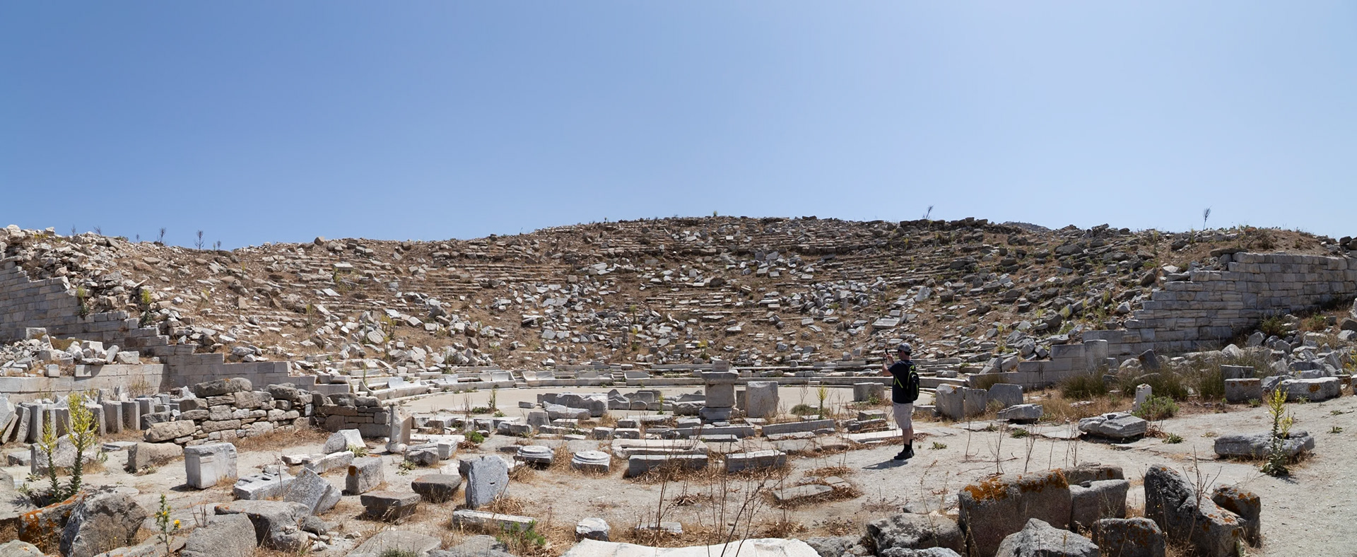 Delos, Greece - May 22nd 2018: A tourist captures the ancient theater's ruins. The site, once a vibrant hub, now stands as a testament to history.