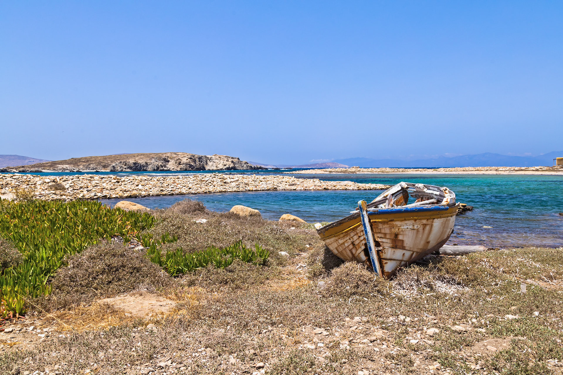 Delos, Greece - May 22nd 2018: A weathered boat rests on the shore, its paint peeling, a testament to time and the elements, adding to the island's rustic charm.