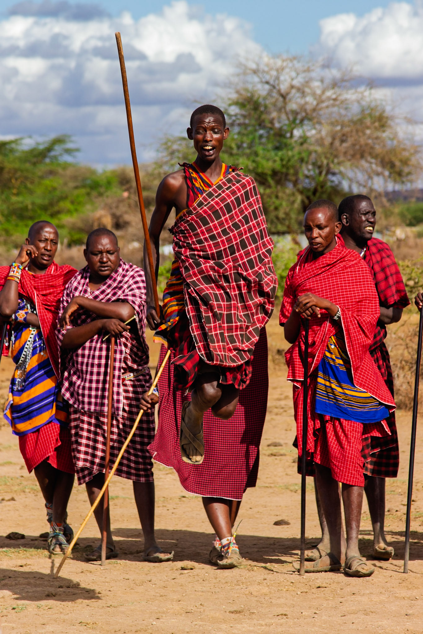 Maasai men in Kenya perform a traditional jumping dance, a display of strength and agility, while wearing traditional shuka.