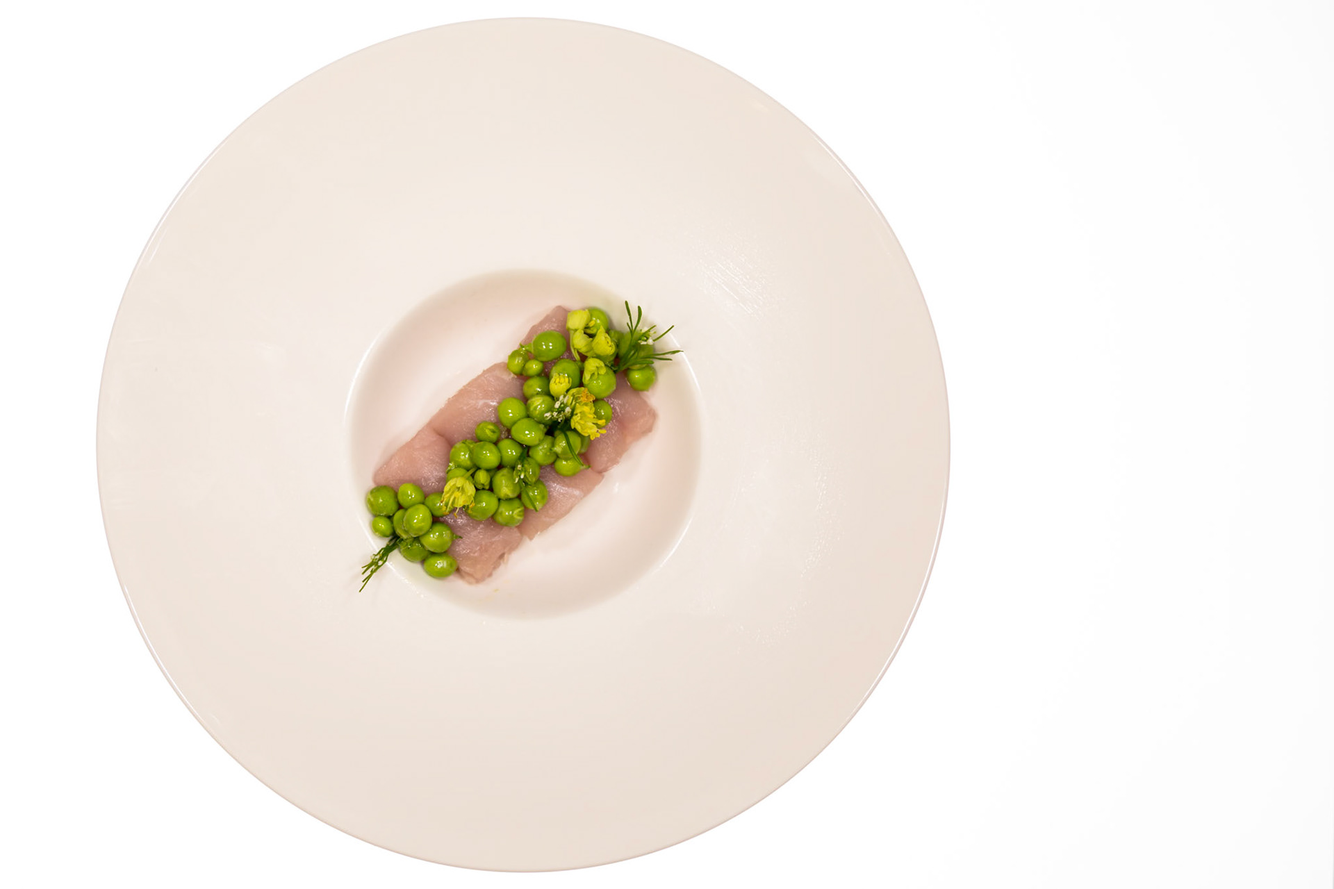 Fog Lark, Portland, Oregon - April 6th 2018: A chef plates a dish of raw fish topped with peas and flowers for a tasting menu.