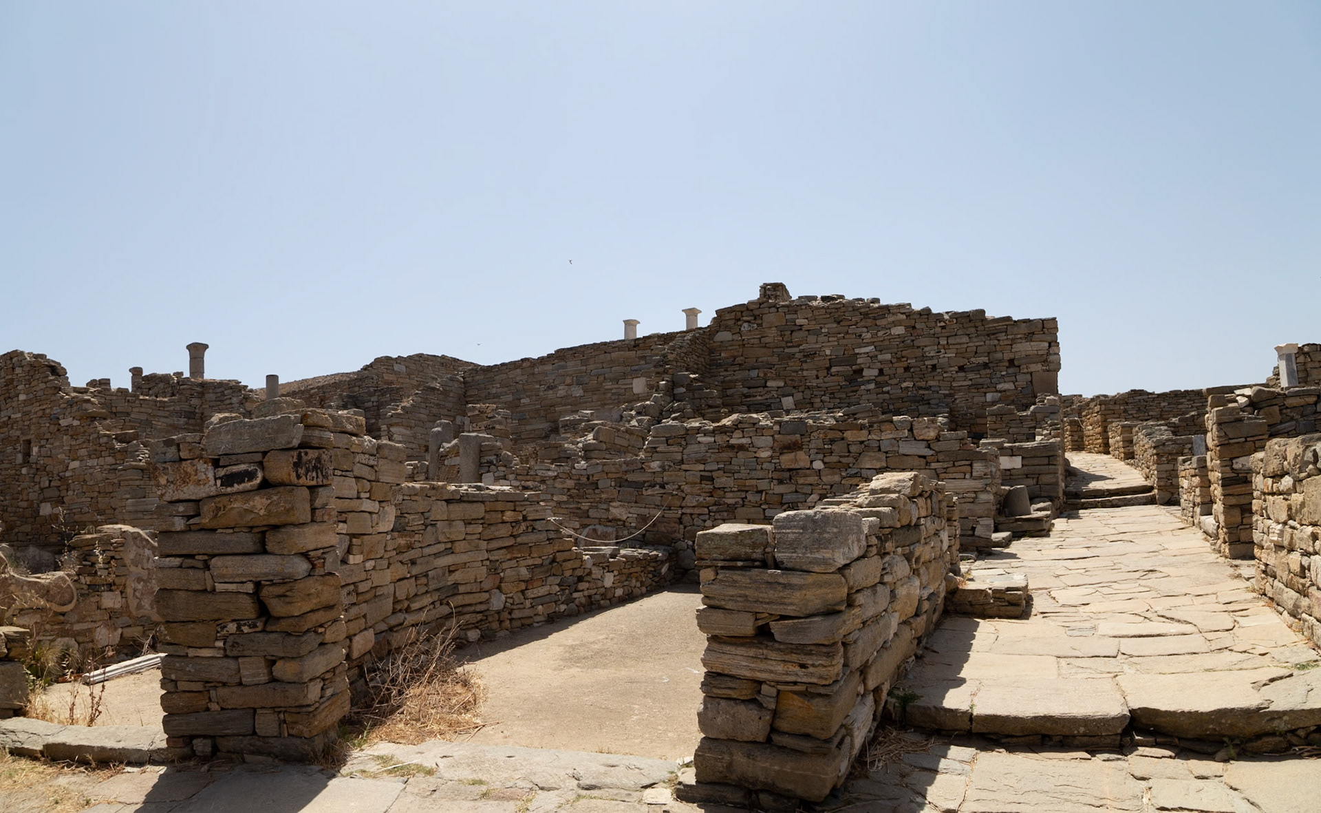 Delos, Greece - May 22nd 2018: Ruins of ancient stone structures and pathways are seen, showcasing the historical significance of the island of Delos.