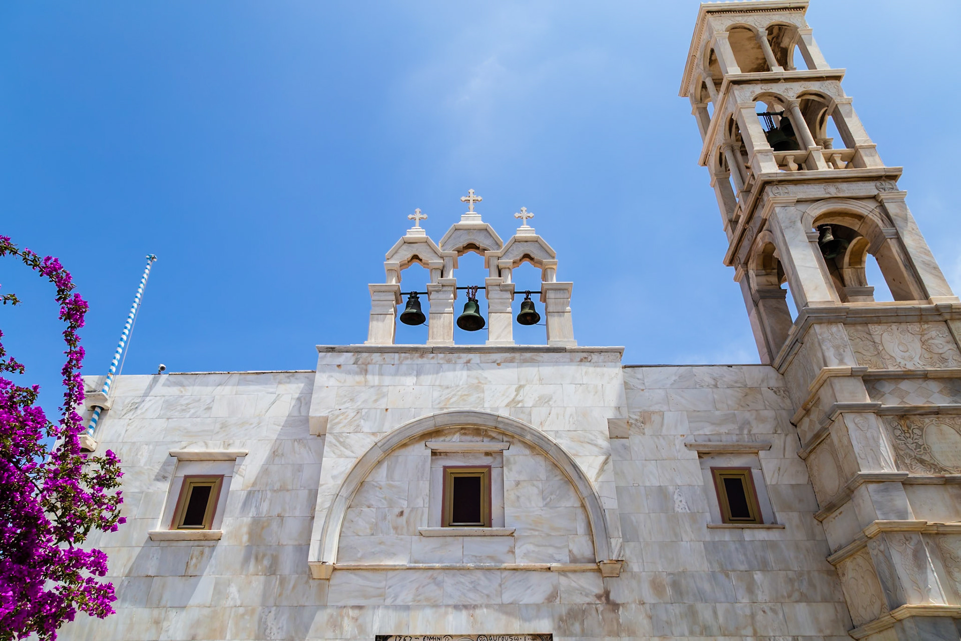 Mykonos, Greece - May 22nd 2018: A low angle shot of the Paraportiani Orthodox Church, a popular tourist destination, against a clear blue sky.