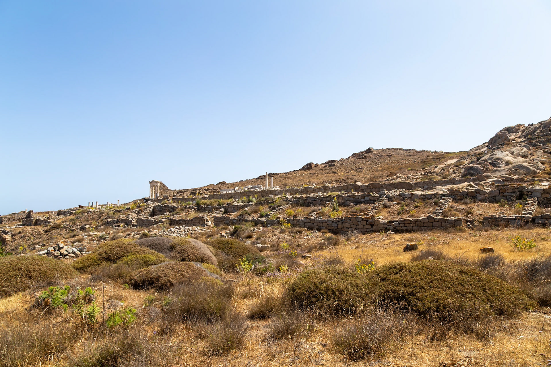 Delos, Greece - May 22nd 2018: Ruins of ancient structures dot the landscape, remnants of a once-thriving civilization, now a historical site for exploration.