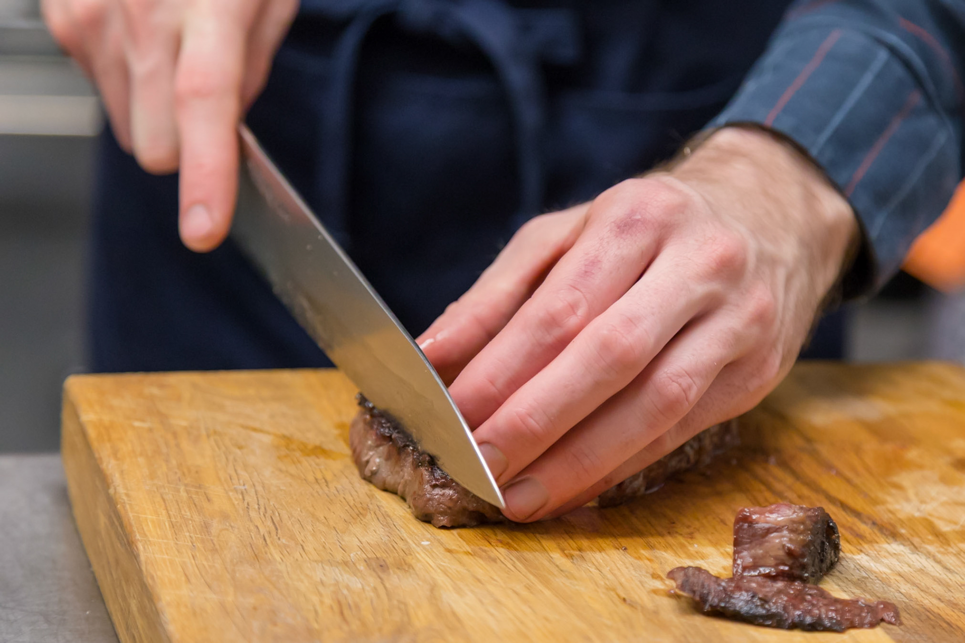 Fog Lark, Portland, Oregon - April 6th 2018: A chef slices a perfectly cooked steak on a wooden cutting board, preparing it for service.
