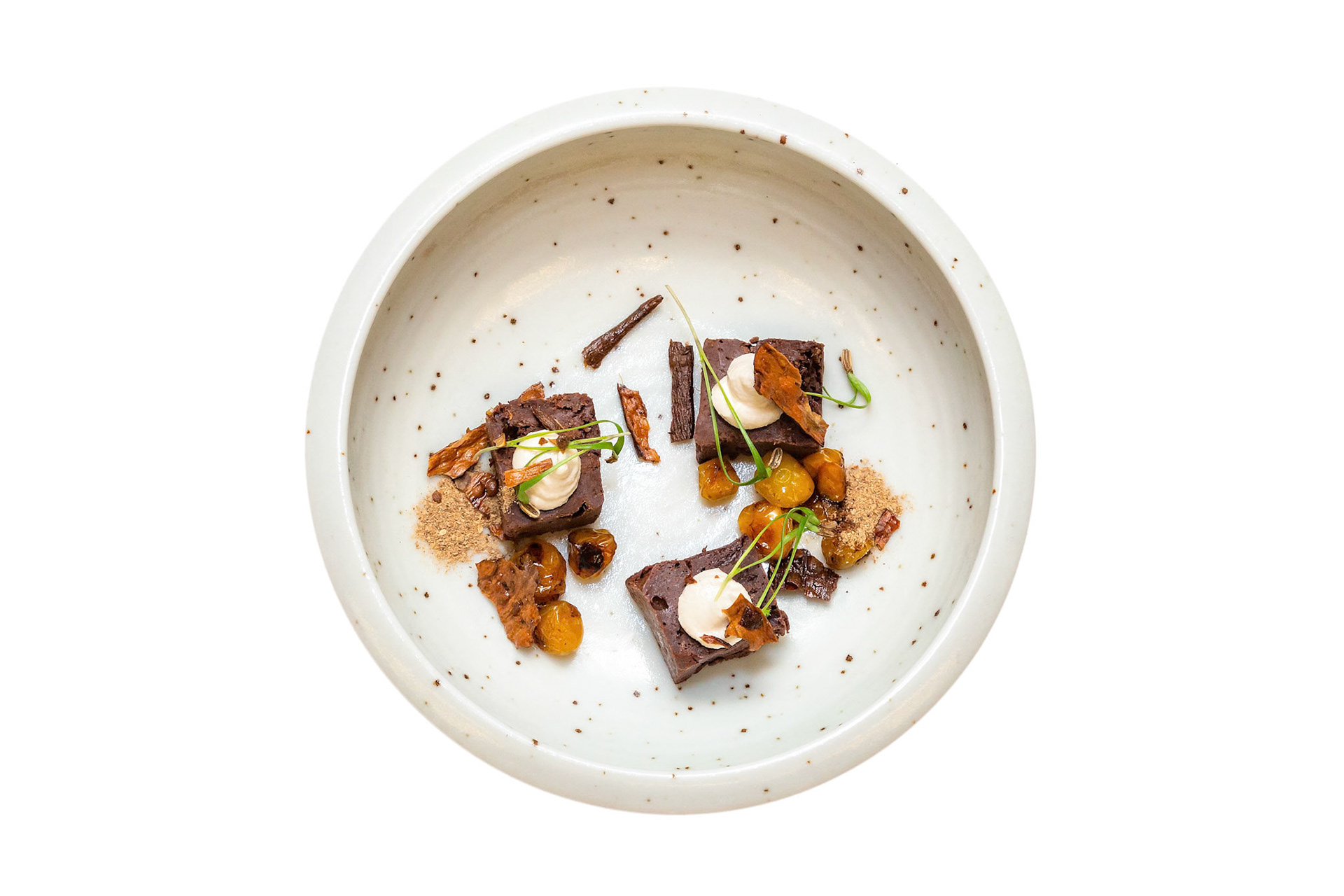 Fog Lark, Portland, Oregon - March 15th 2019: A chef plates a dessert with brownies, cream, and candied fruit for a fine dining experience.