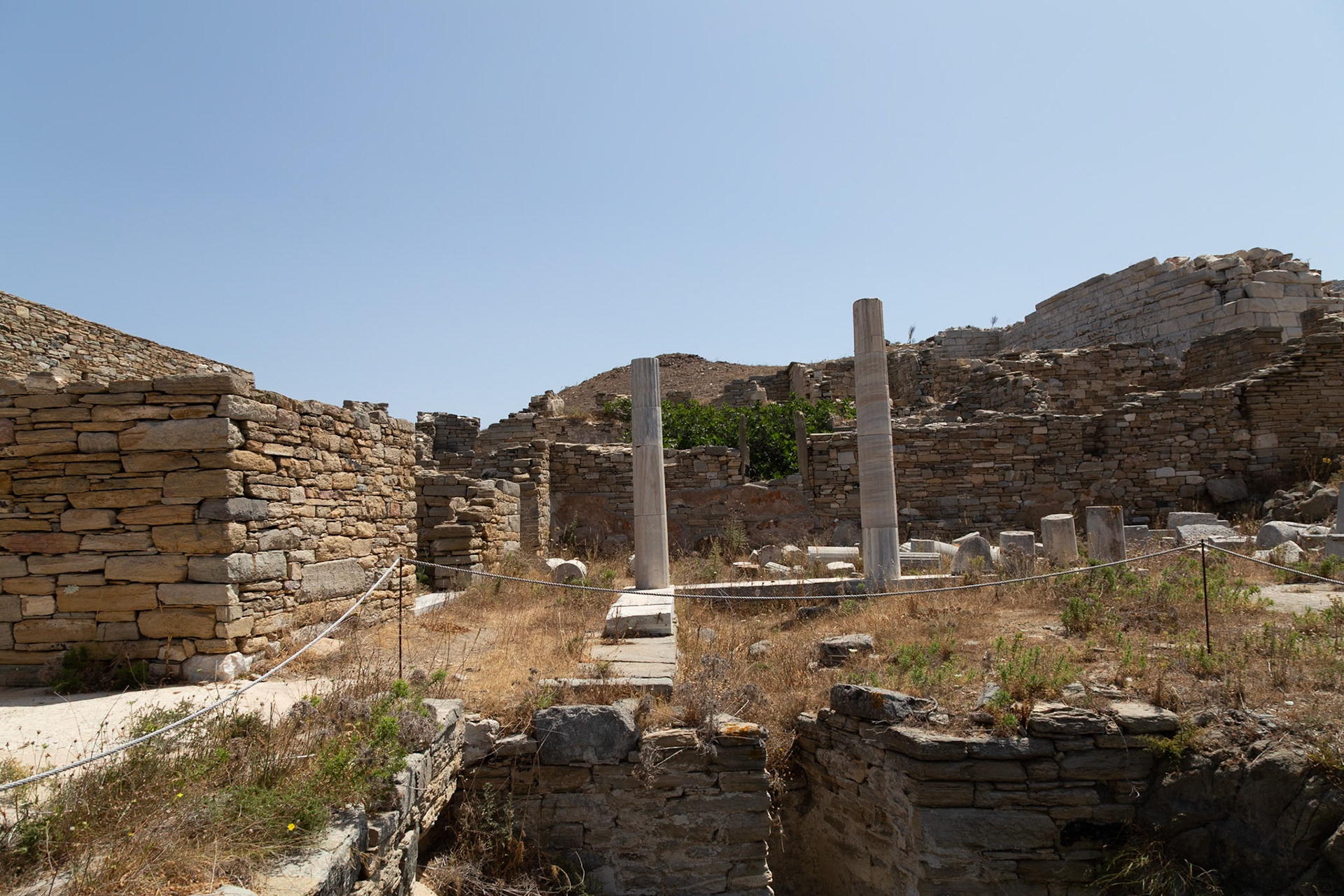Delos, Greece - May 22nd 2018: Ruins of an ancient structure stand against a clear sky. The site is a reminder of the island's rich history and cultural significance.