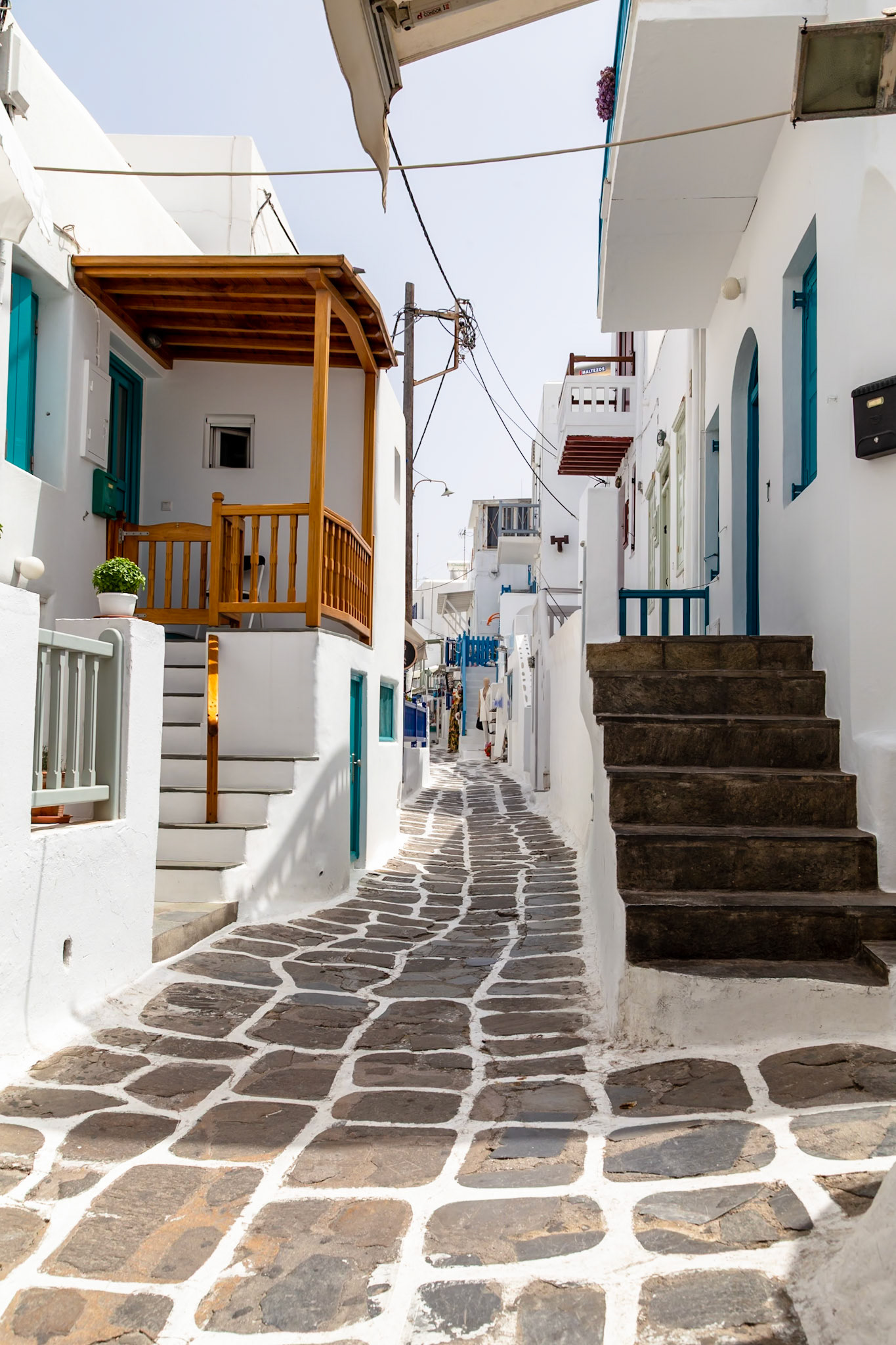 Mykonos, Greece - May 23rd 2018: A narrow street with white buildings and stone pavement is shown, capturing the island's unique architecture.