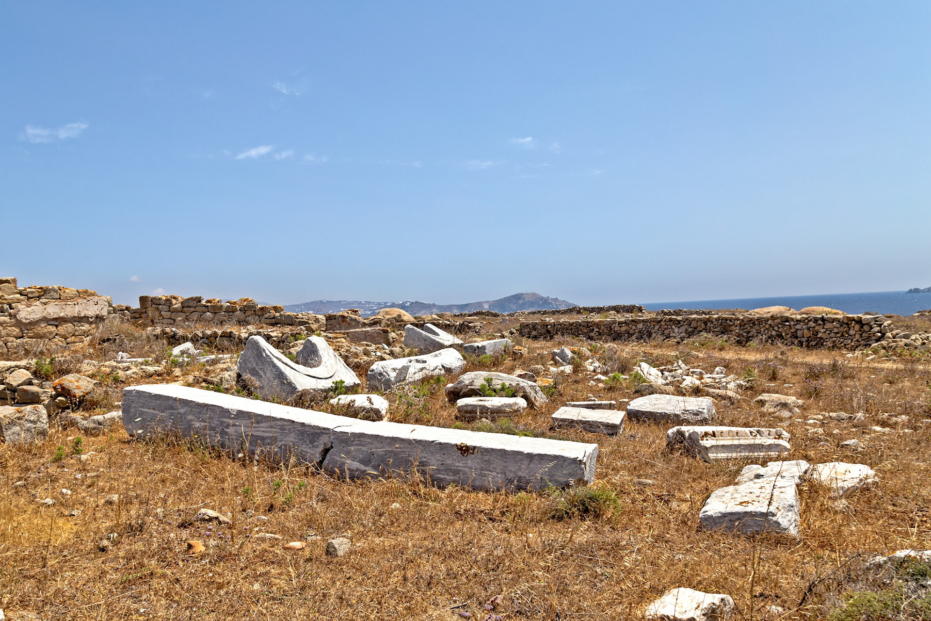 Delos, Greece - May 22nd 2018: Ruins of ancient structures lay scattered across the landscape, remnants of a once-thriving civilization, now a historical site.