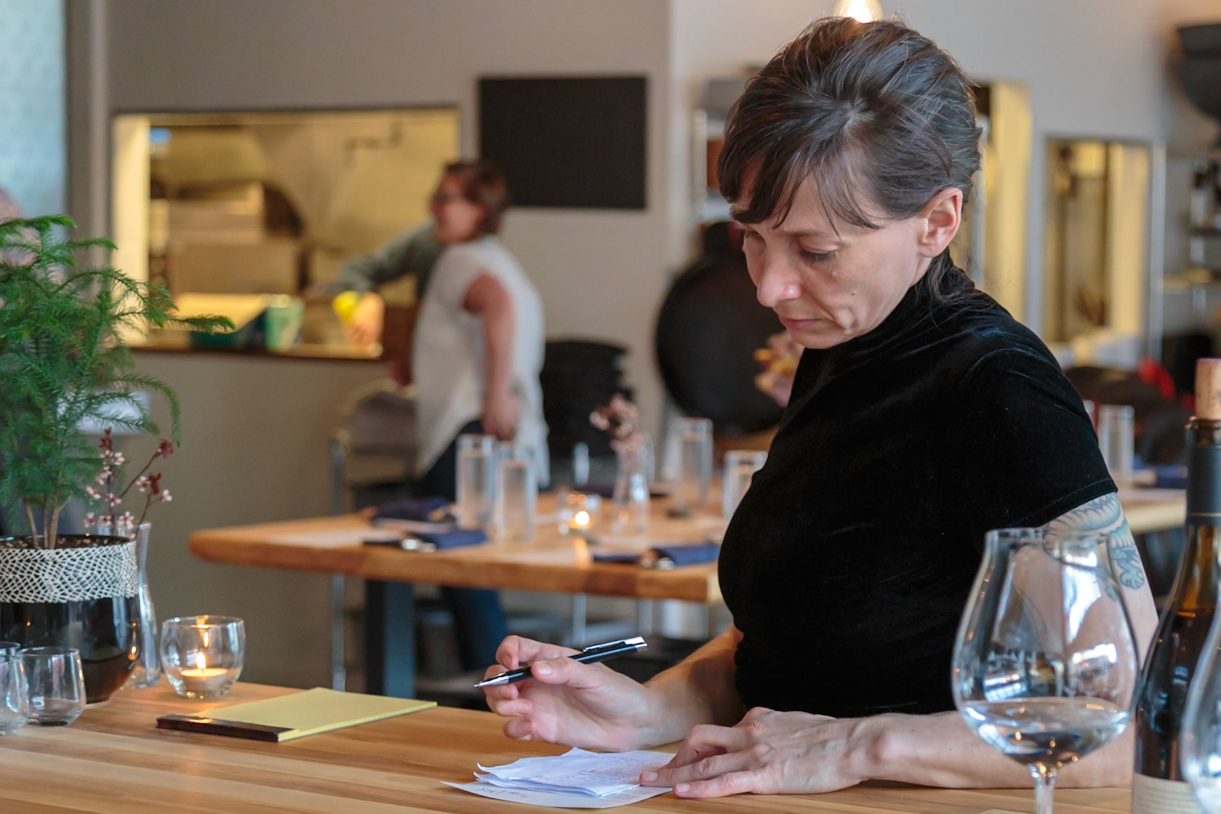 Fog Lark, Portland, Oregon - April 6th 2018: A woman reviews notes at a restaurant table, possibly a manager or owner planning the day's service.