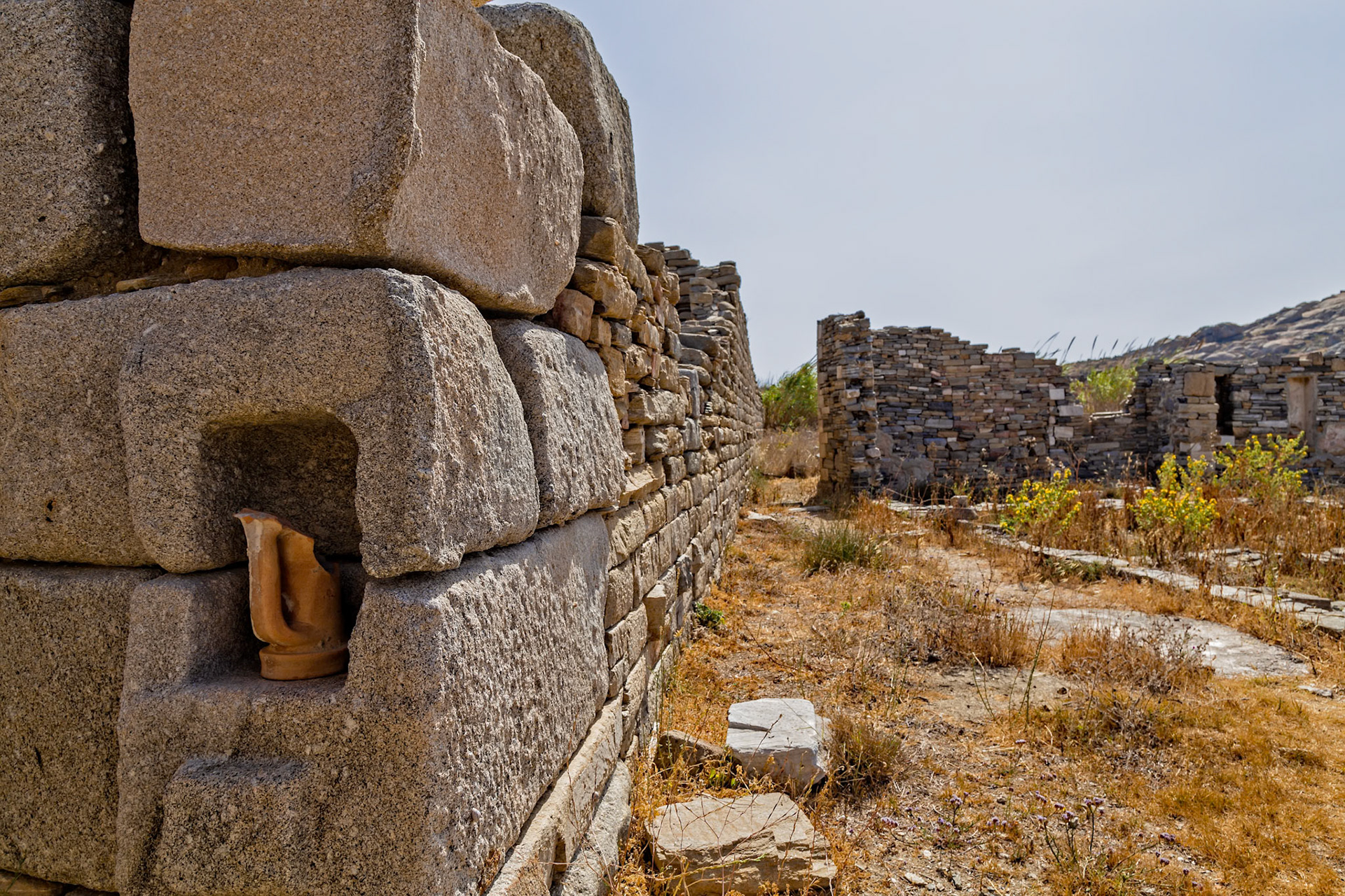 Delos, Greece - May 22nd 2018: A broken vase sits in the ruins of Delos, a Greek island and archaeological site, showcasing ancient architecture and artifacts.