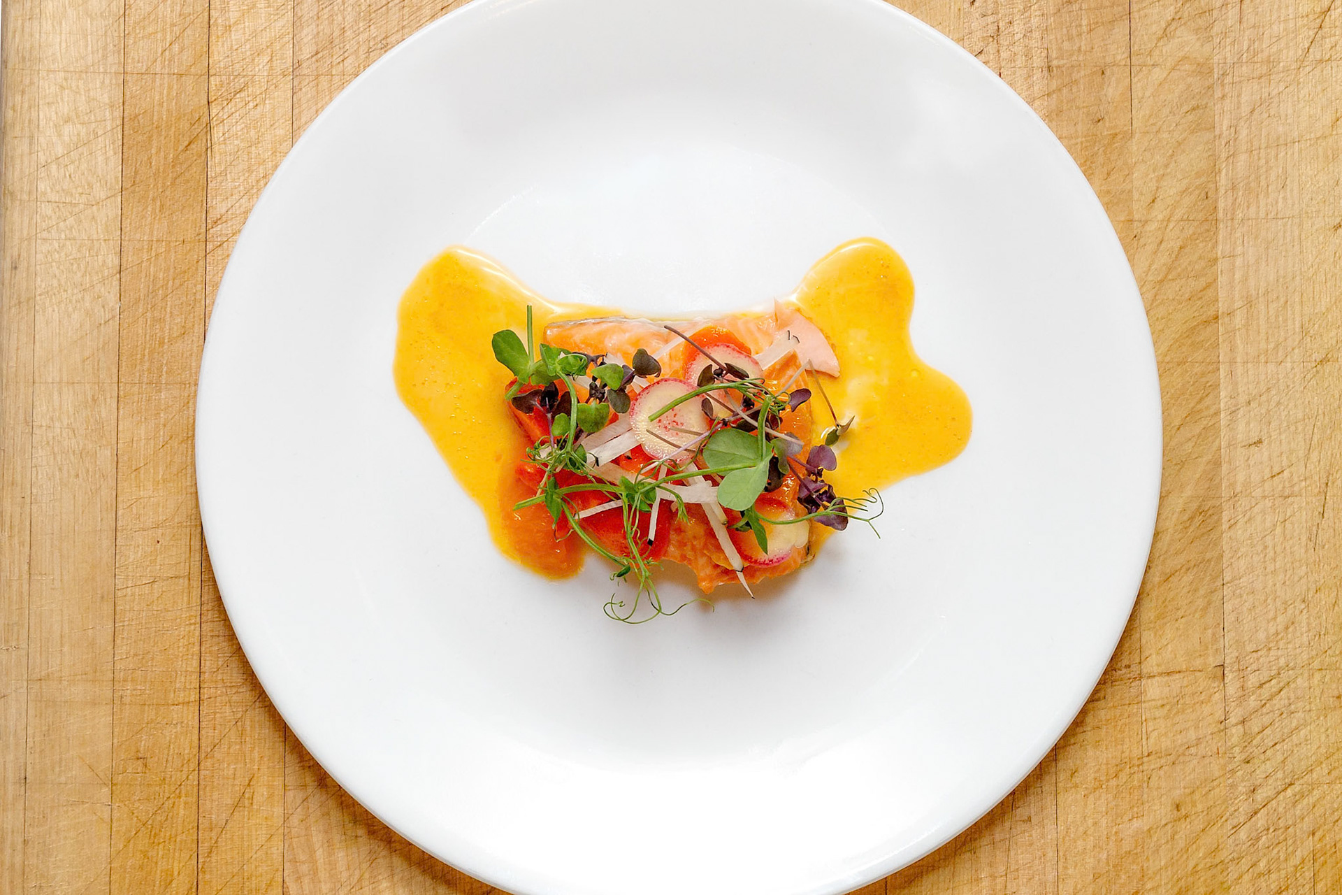Fog Lark, Portland, Oregon - March 15th 2019: A chef plates a salmon dish with microgreens and sauce, showcasing culinary artistry.