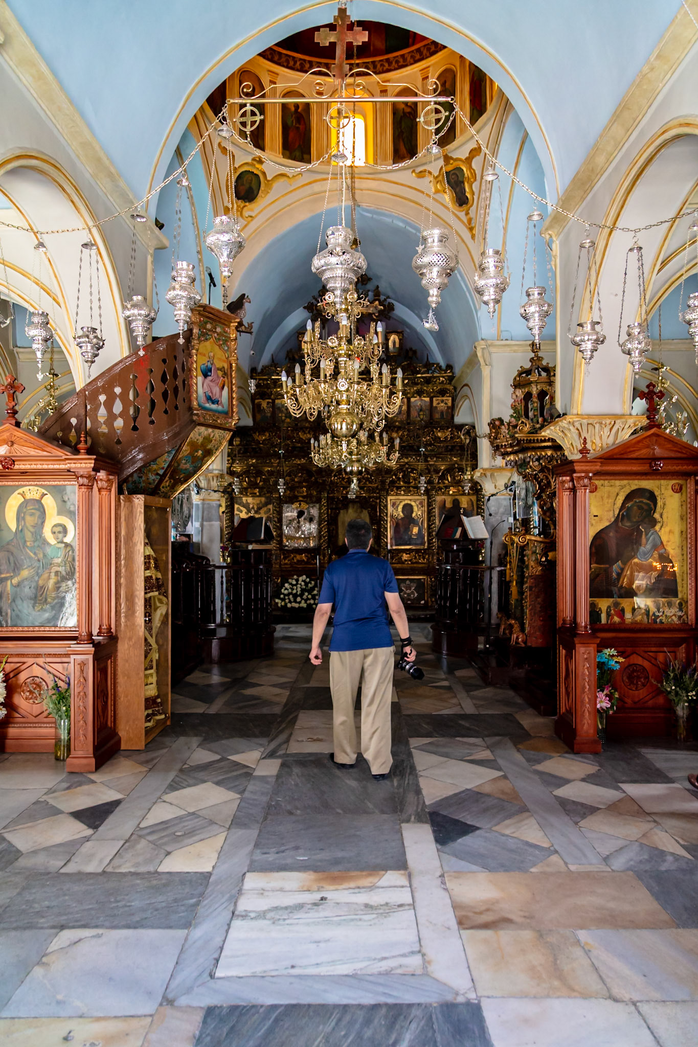 Mykonos, Greece - May 22nd 2018: A tourist explores the Panagia Paraportiani church, admiring its architecture and religious icons.