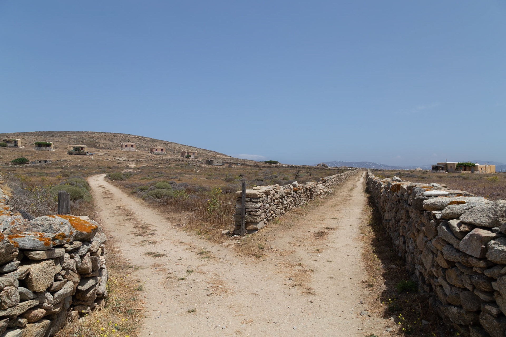 Delos, Greece - May 22nd 2018: A fork in the road on Delos Island, Greece. The paths are lined with stone walls, leading to ancient ruins on a sunny day.