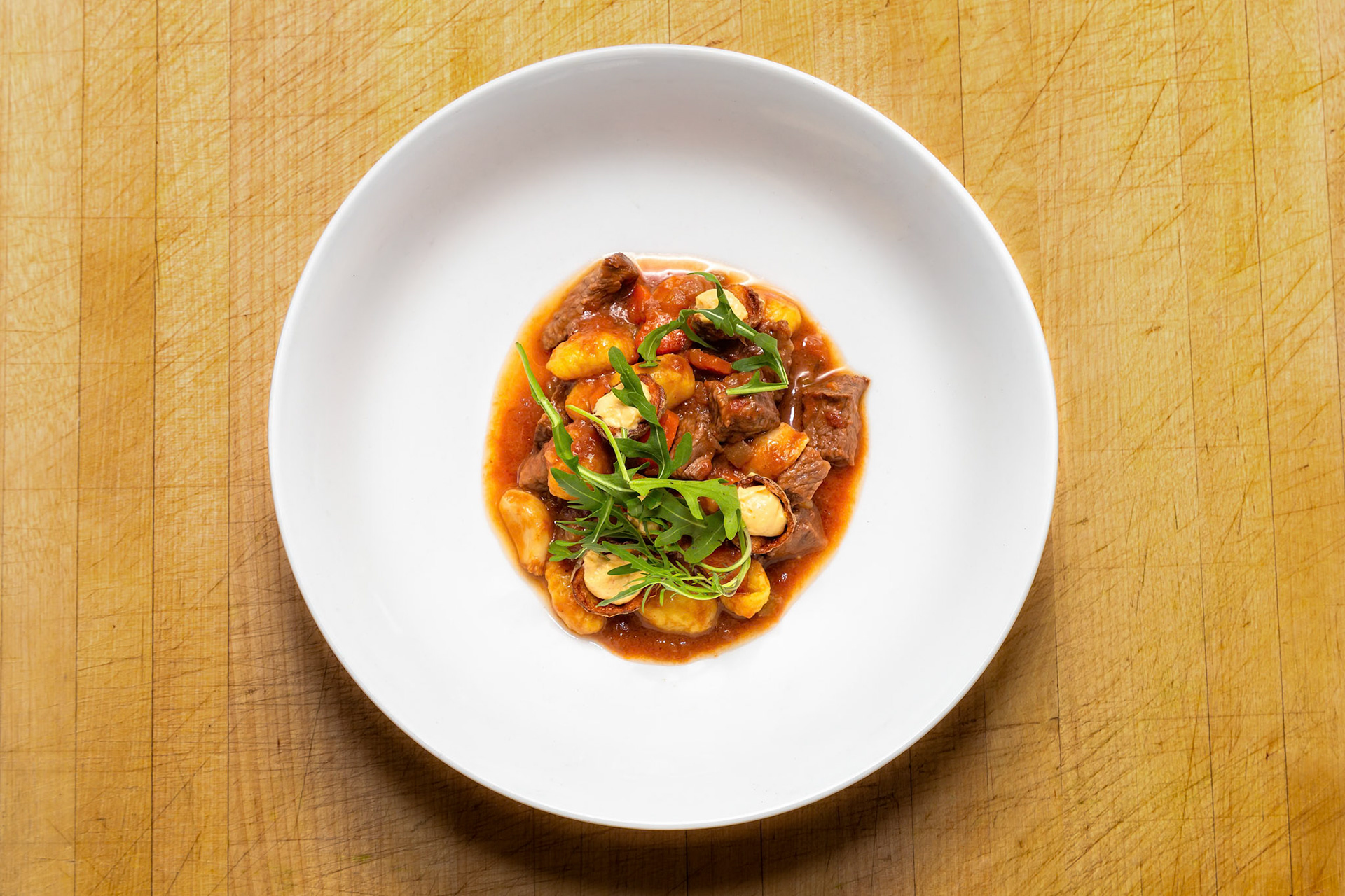 Fog Lark, Portland, Oregon - March 15th 2019: A chef plates a dish of gnocchi and beef stew, garnished with fresh arugula, for a food photography shoot.