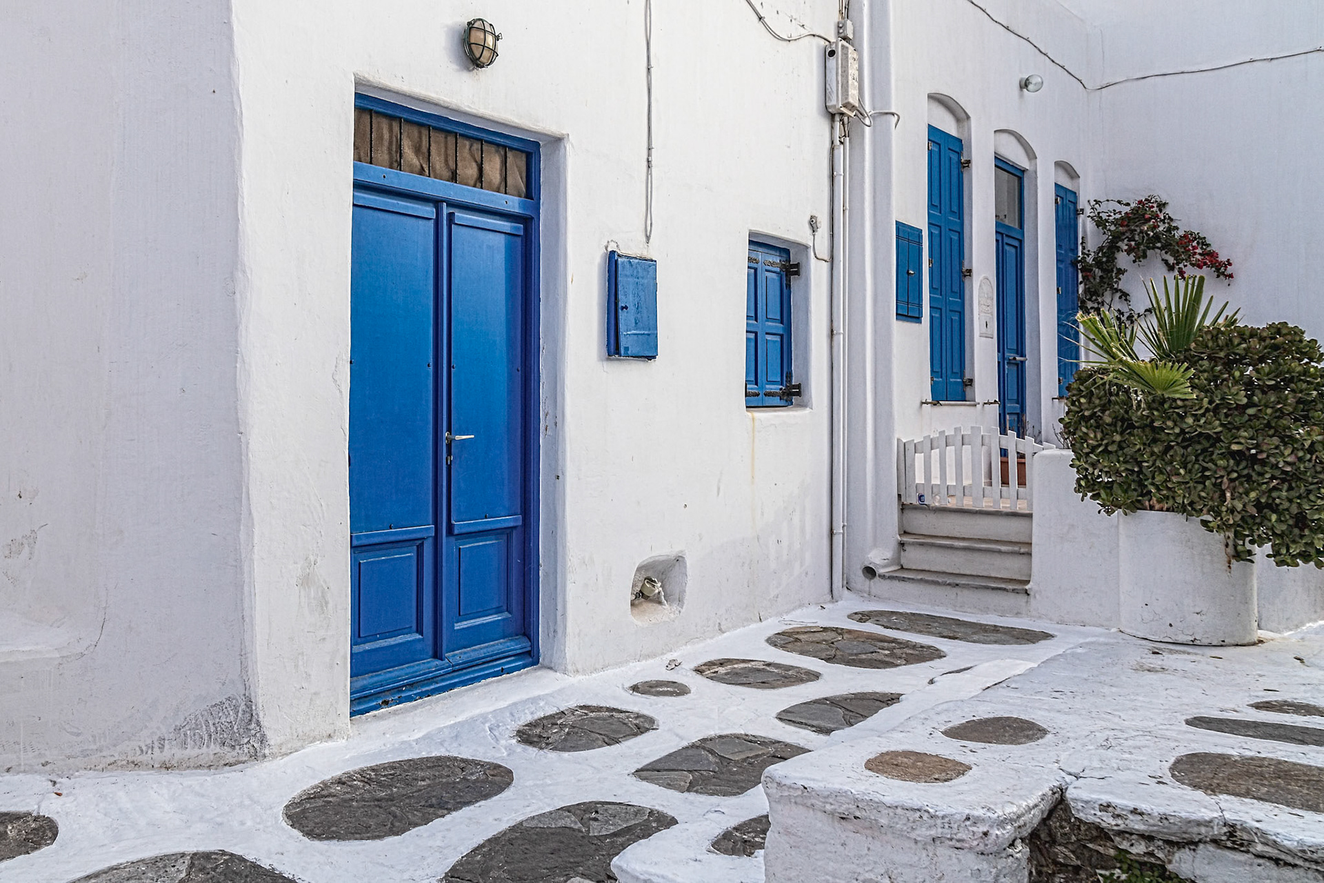 Mykonos, Greece - May 23rd 2018: A typical street scene with white walls and blue doors/shutters, showcasing the island's iconic architecture.