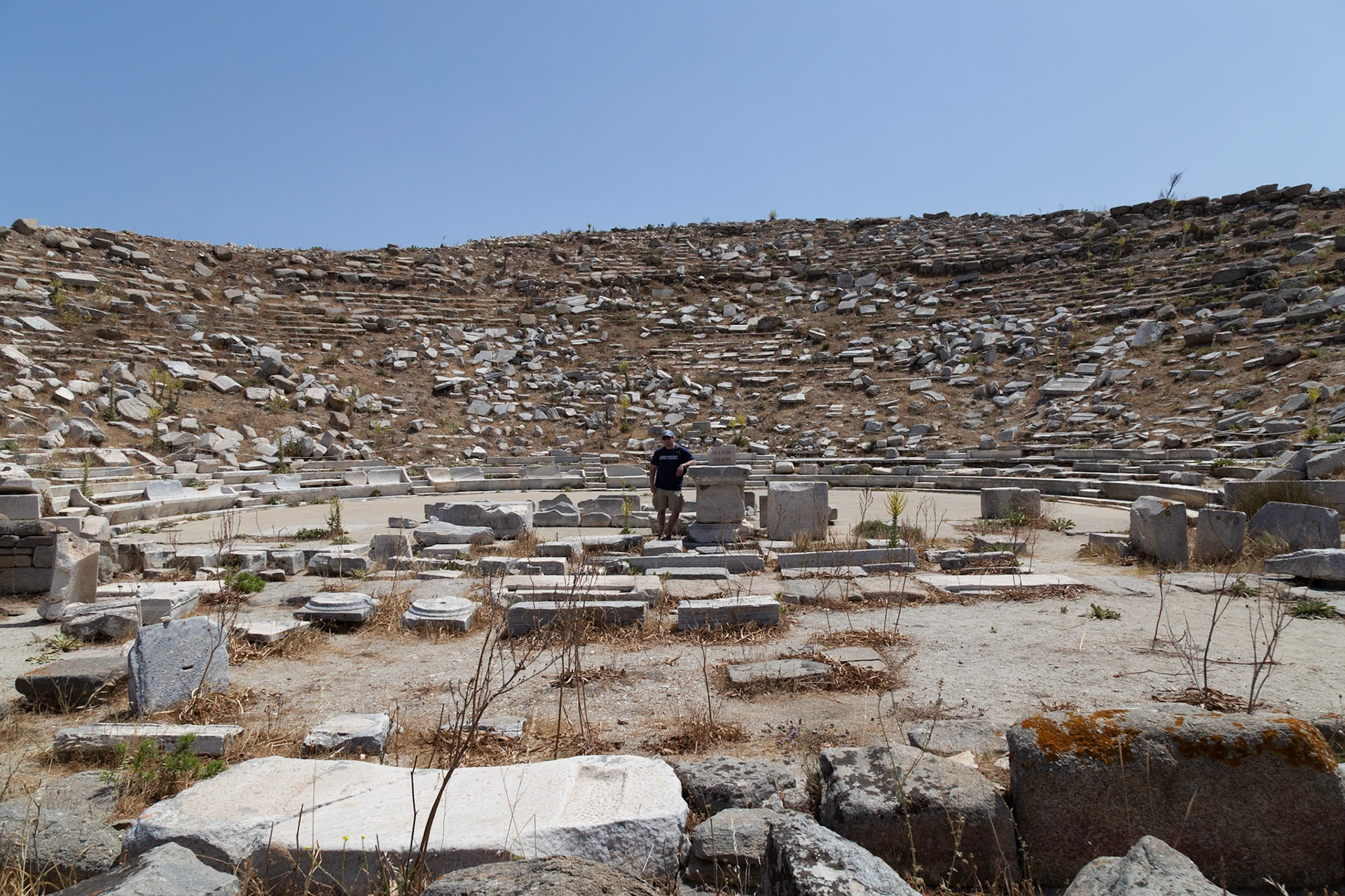 Delos, Greece - May 22nd 2018: A tourist explores the ancient Theatre of Delos, taking in the historical site and its architectural ruins.