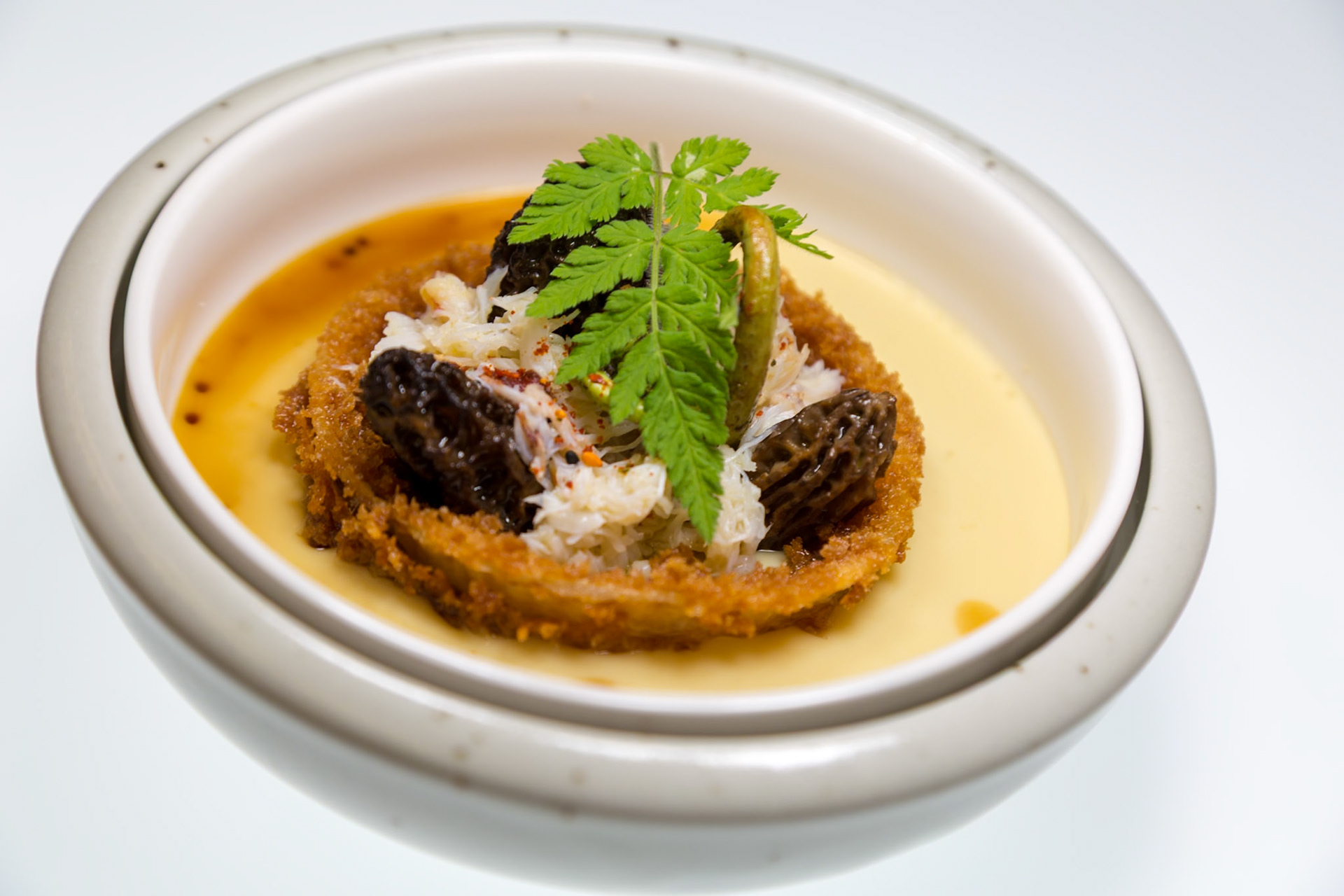 Fog Lark, Portland, Oregon - April 6th 2018: A culinary creation featuring morel mushrooms, crab, and a crispy element in a creamy sauce.