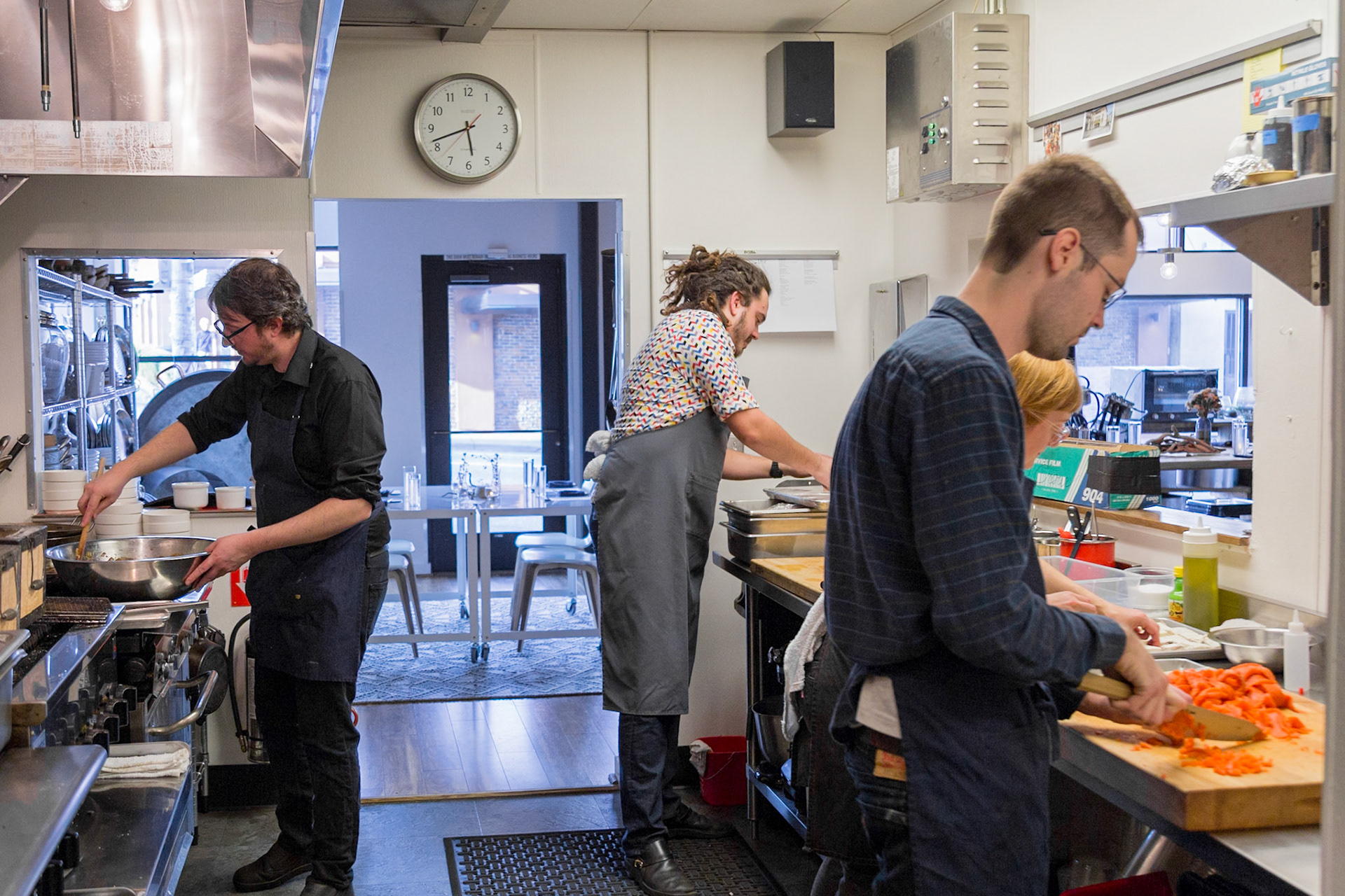 Fog Lark, Portland, Oregon - April 6th 2018: Chefs prep food in a busy kitchen, stirring, chopping, and organizing ingredients for service.