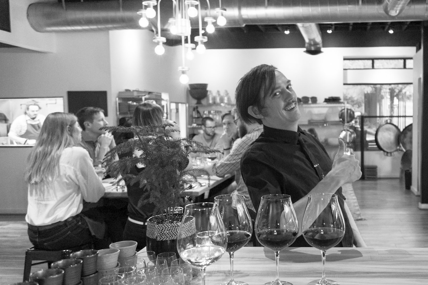 Fog Lark, Portland, Oregon - April 6th 2018: A server gives a thumbs up at a wine tasting event, with guests enjoying the experience.
