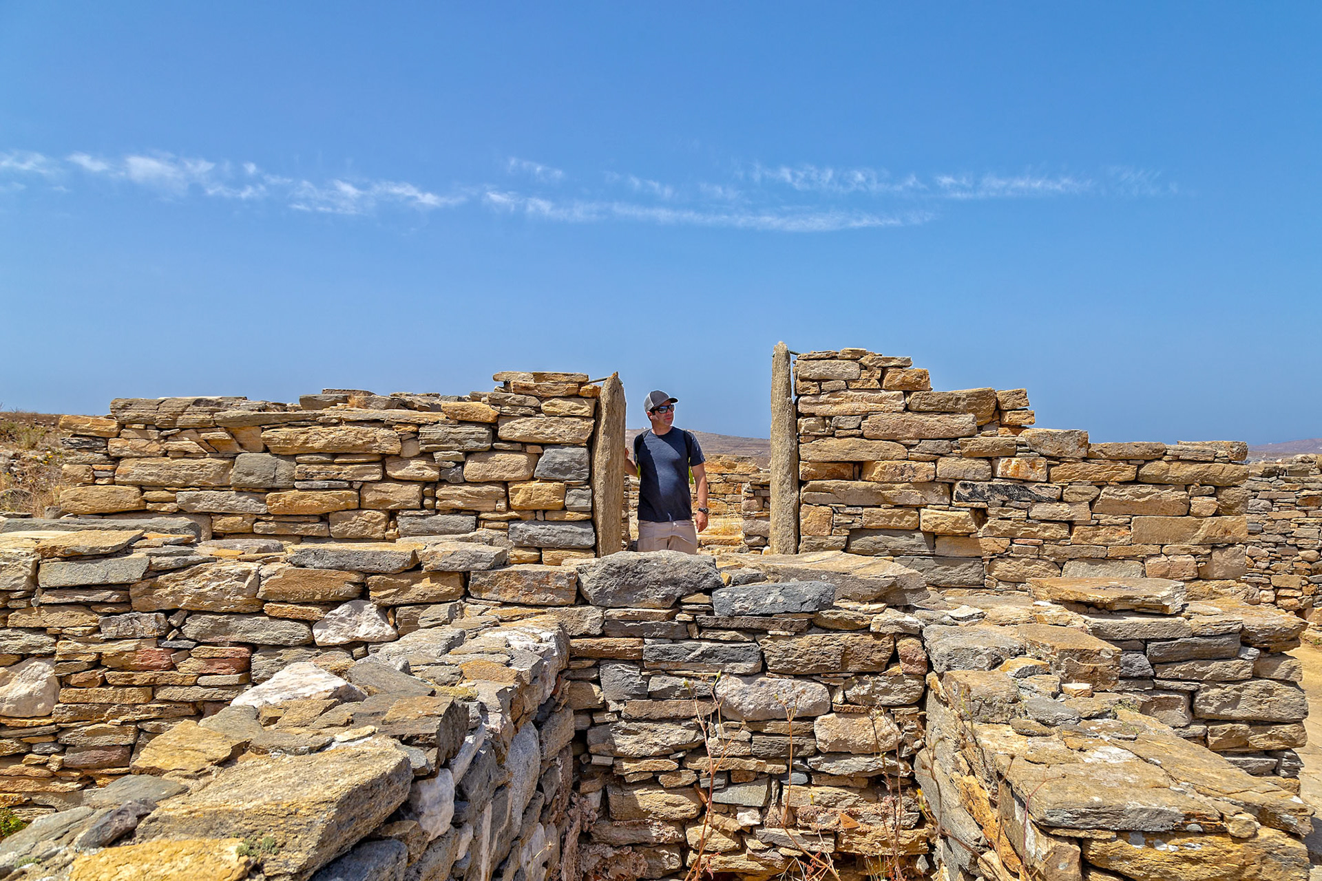 Delos, Greece - May 22nd 2018: A man explores the ancient ruins of Delos, a UNESCO World Heritage site, to learn about the history and culture of the island.