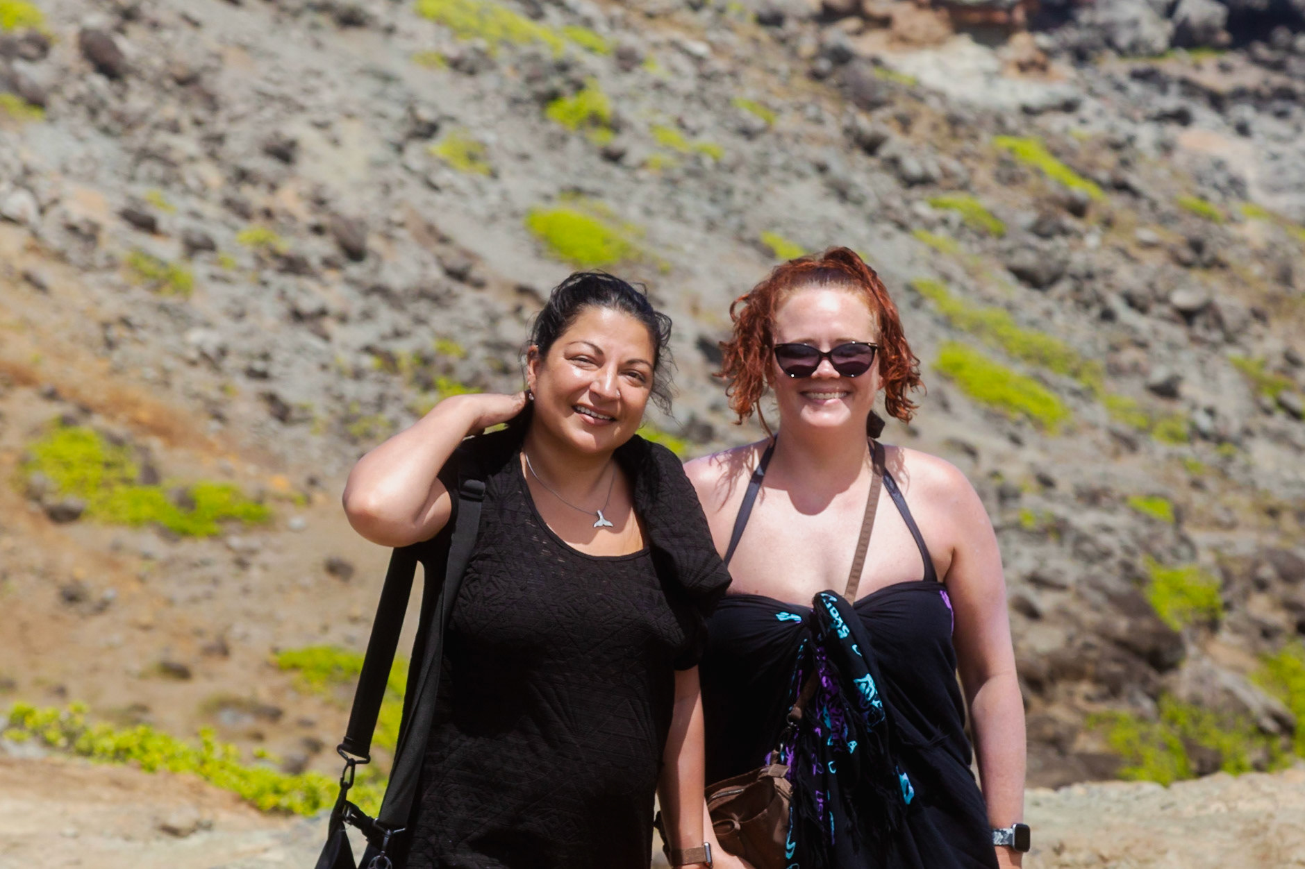 Maui, Hawaii, USA - April 9th 2022: Two smiling women pose for a photo in front of a rocky hillside, enjoying a sunny day on vacation.