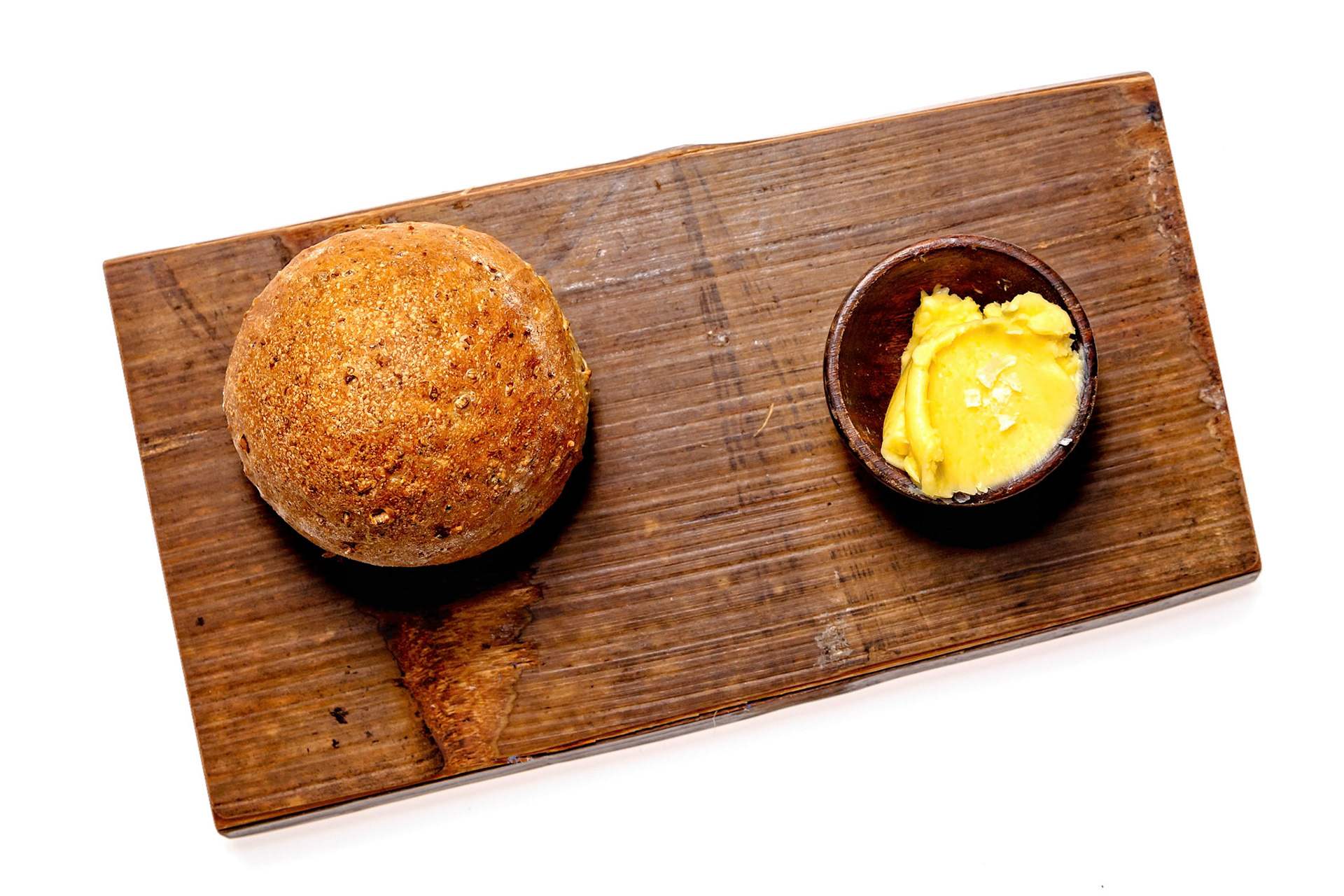 Fog Lark, Portland, Oregon - March 15th 2019: A rustic wooden board displays a round loaf of bread and a small bowl of butter, ready to be enjoyed.