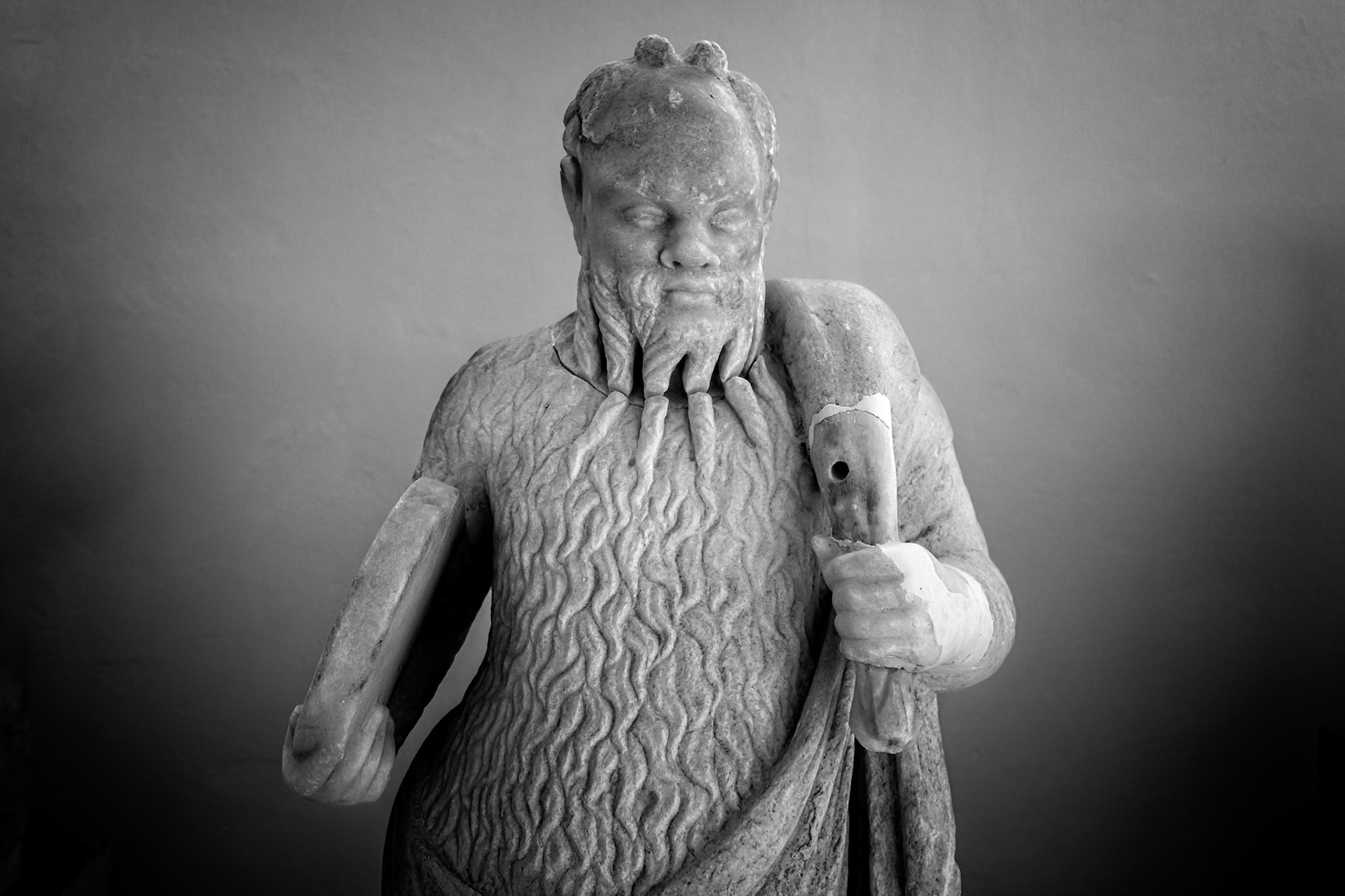 Delos, Greece - May 22nd 2018: A weathered marble statue of Silenus, a companion and tutor to the wine god Dionysus, stands in Delos, showcasing ancient Greek artistry.