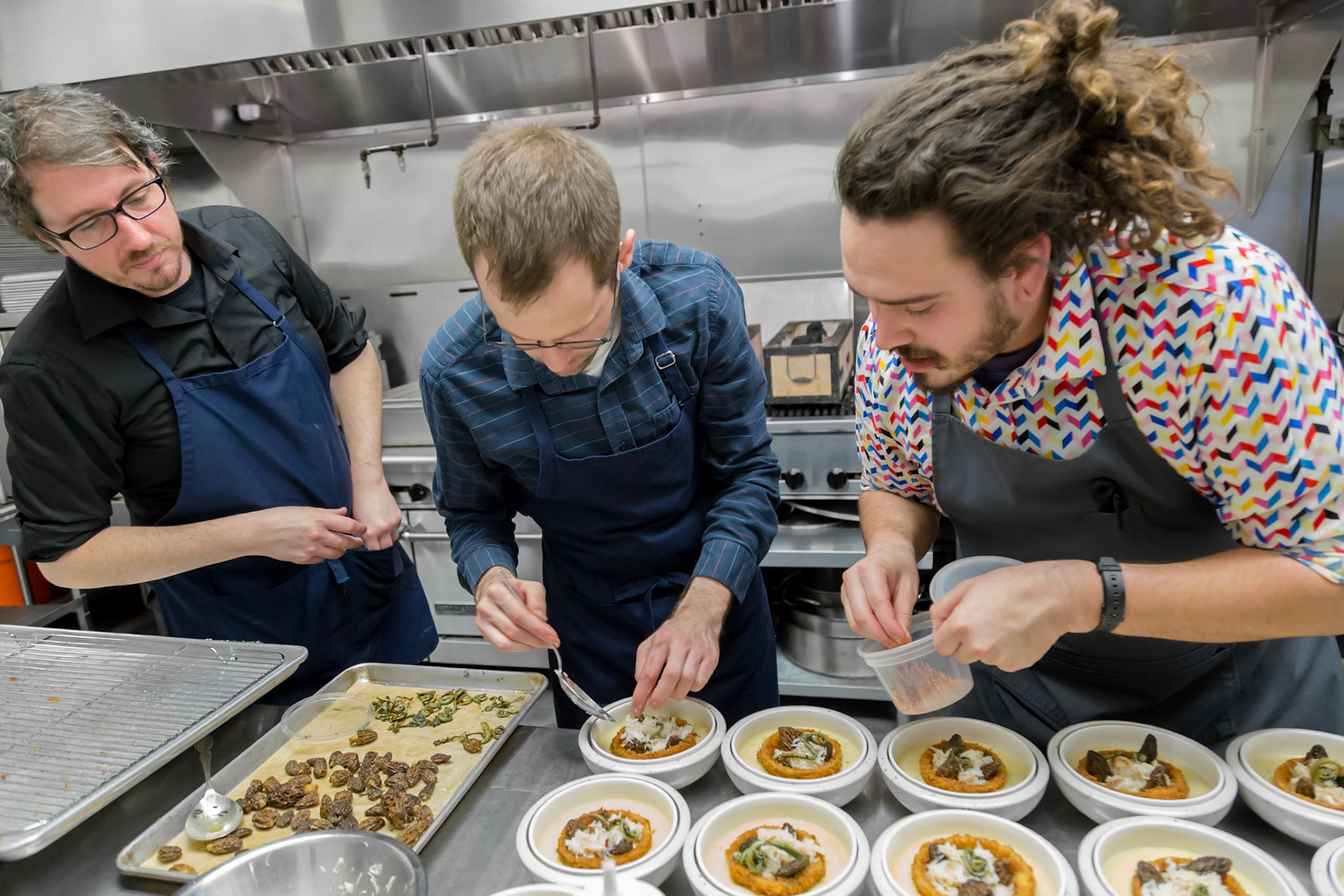 Fog Lark, Portland, Oregon - April 6th 2018: Three chefs plate a dish with morel mushrooms, likely for a special event or tasting menu.