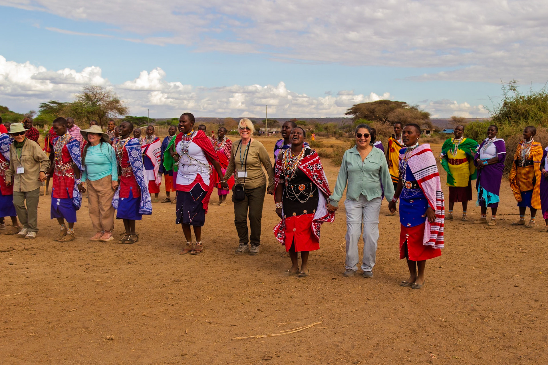 Tourists join Maasai women in Kenya for a traditional dance, fostering cultural exchange and understanding in their village.