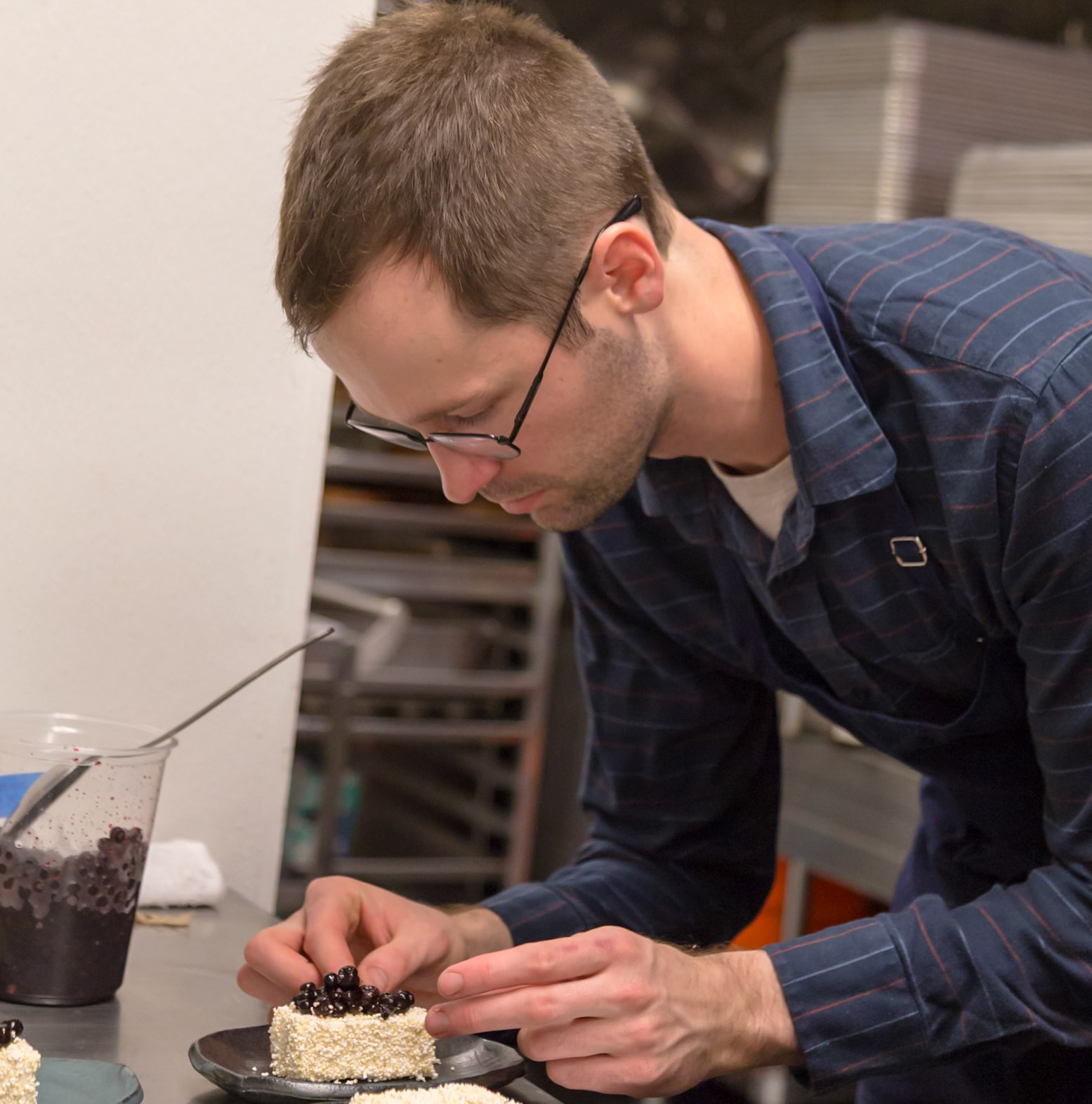 Fog Lark, Portland, Oregon - April 6th 2018: A pastry chef carefully places berries on a small cake, adding the finishing touches.