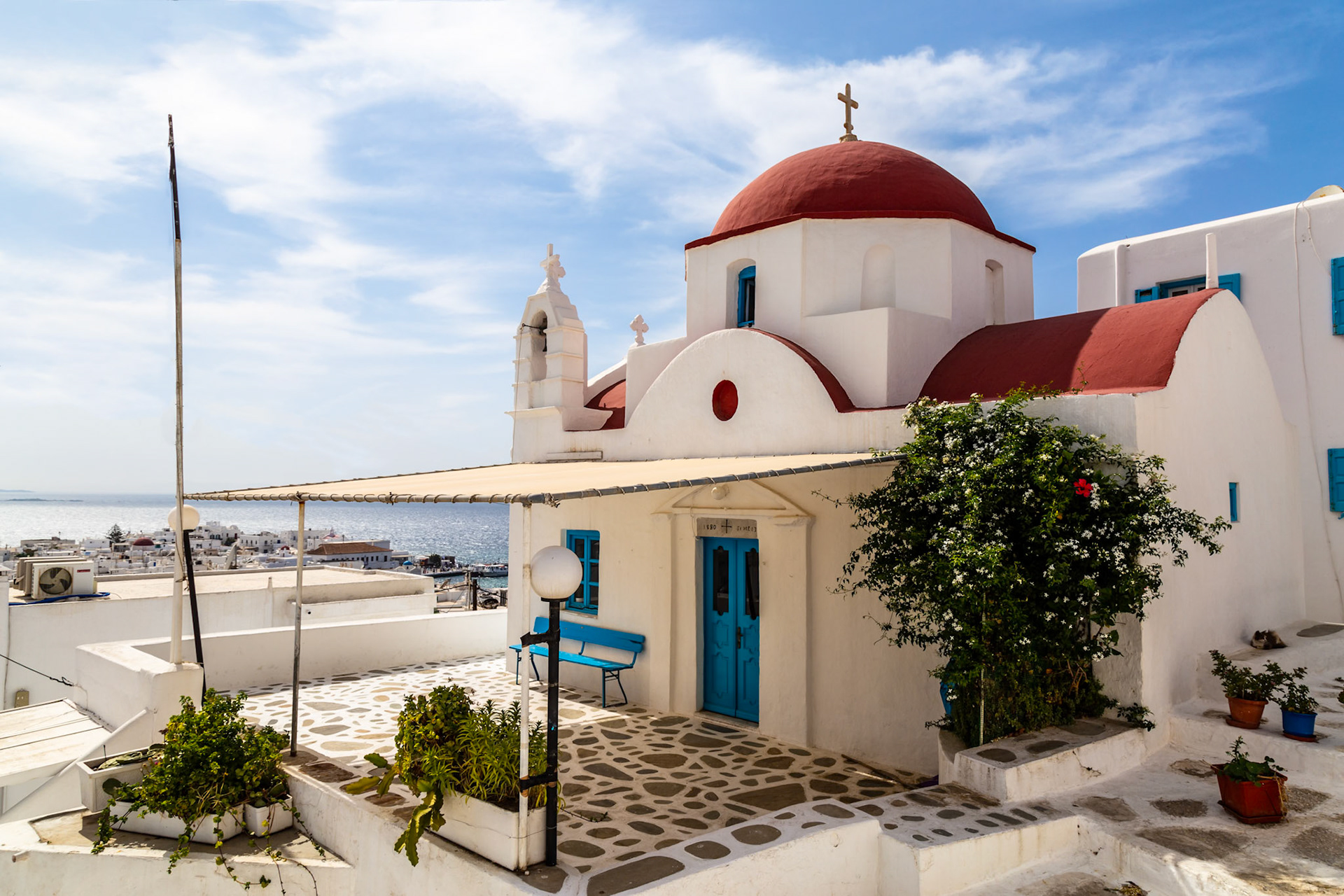 Mykonos, Greece - May 22nd 2018: A traditional Greek Orthodox church with its iconic red dome stands proudly against the blue sky.