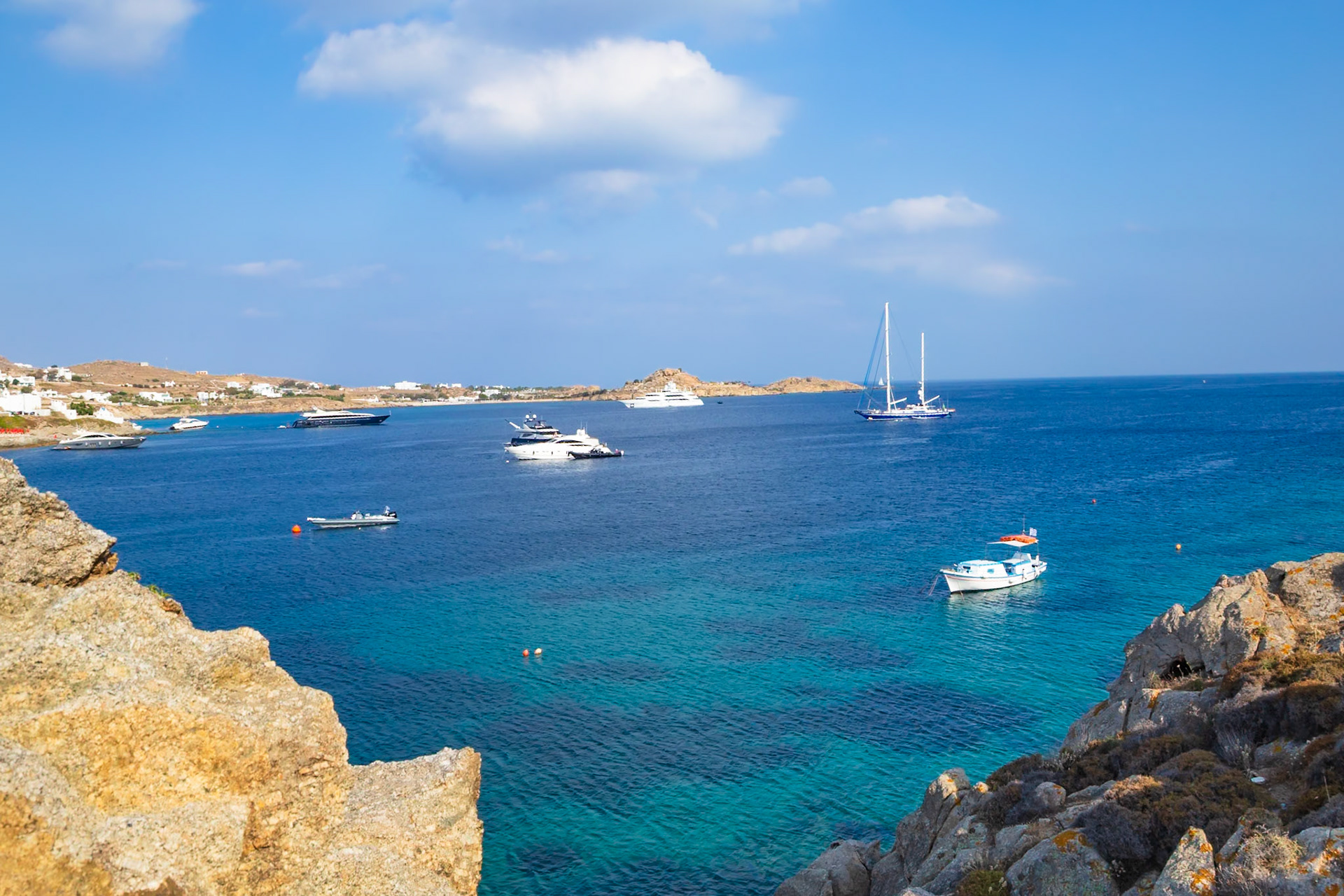 Psarou Beach, Mykonos, Greece - May 24th 2018: Yachts and boats dot the Aegean Sea, offering a glimpse into the luxurious lifestyle of the island.
