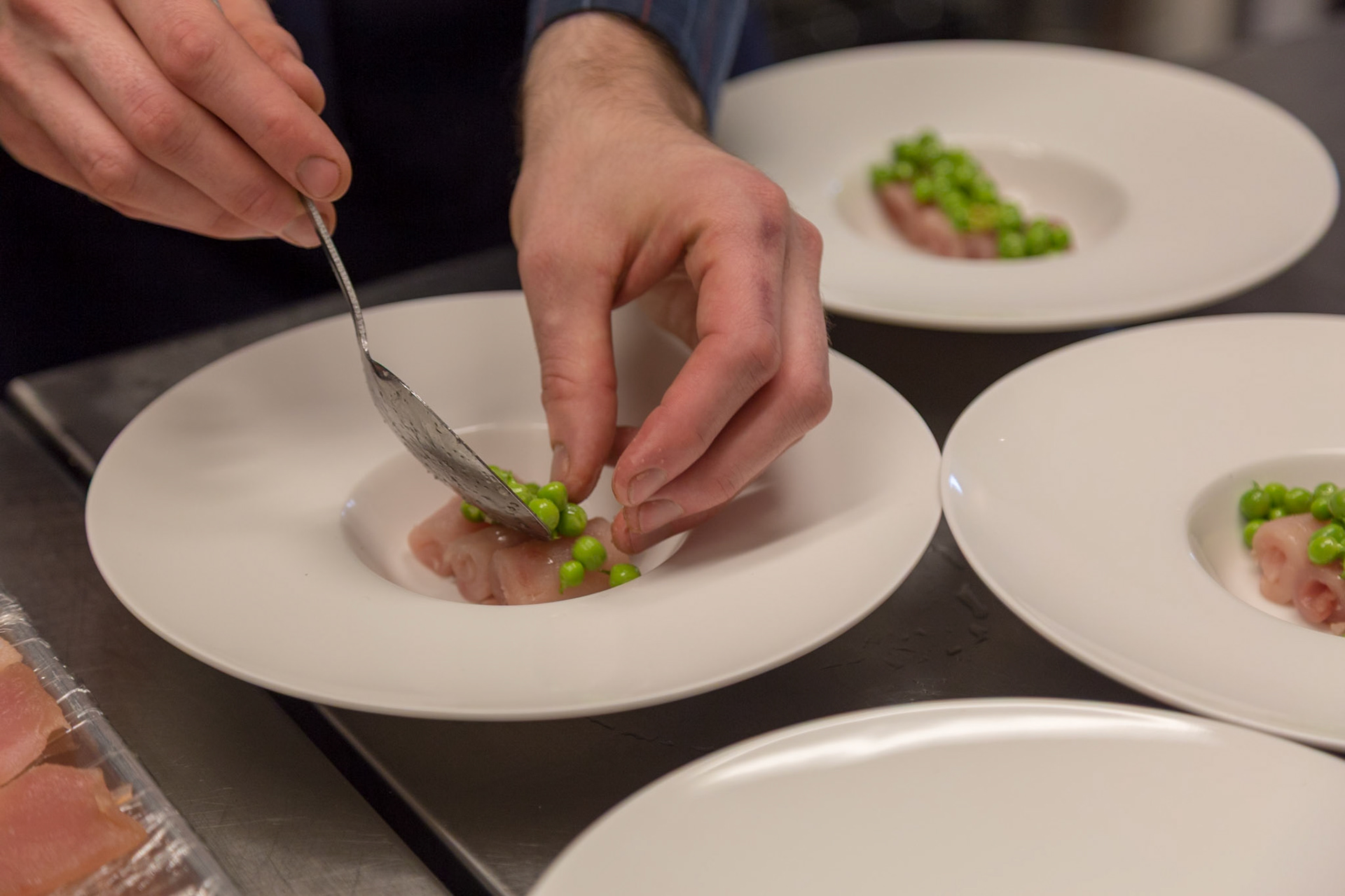 Fog Lark, Portland, Oregon - April 6th 2018: A chef plates a dish with fish and peas, ensuring a visually appealing presentation.