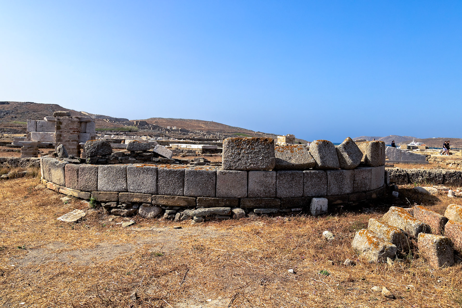 Delos, Greece - May 22nd 2018: Ruins of an ancient structure stand against a clear blue sky, showcasing the historical significance of Delos as a UNESCO World Heritage site.