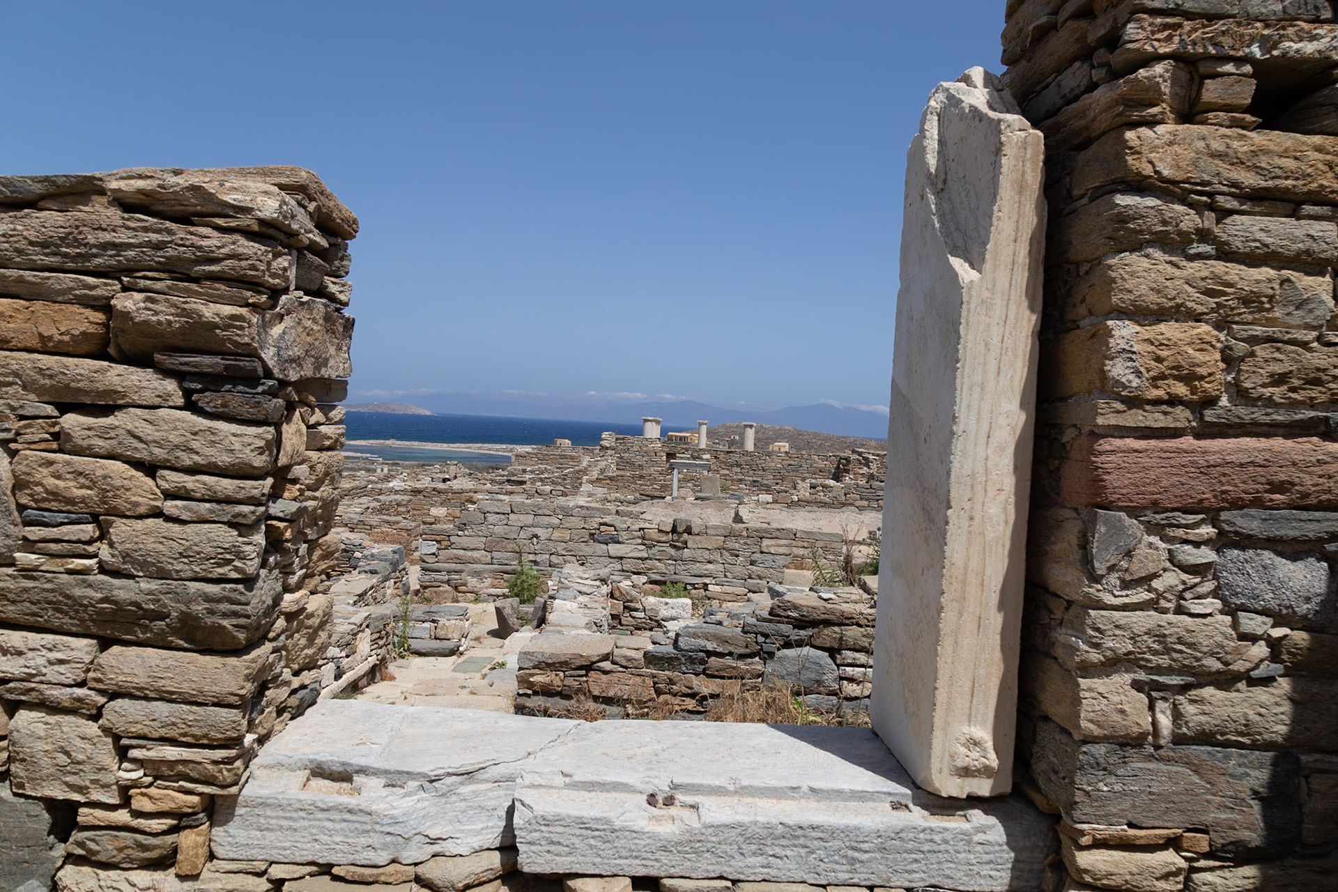 Delos, Greece - May 22nd 2018: Ruins of ancient buildings are seen through a stone window. This is a popular tourist destination for those interested in history.