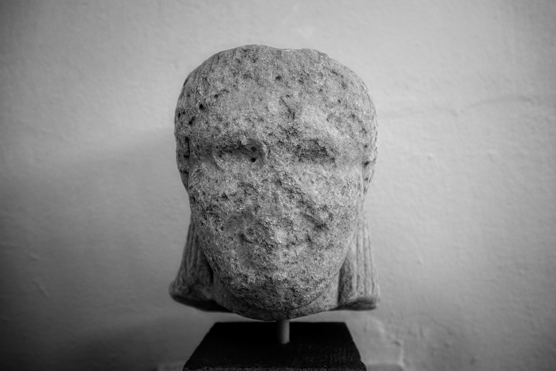 Delos, Greece - May 22nd 2018: An ancient, weathered stone head rests on a stand, showcasing the artistry and history of Delos.