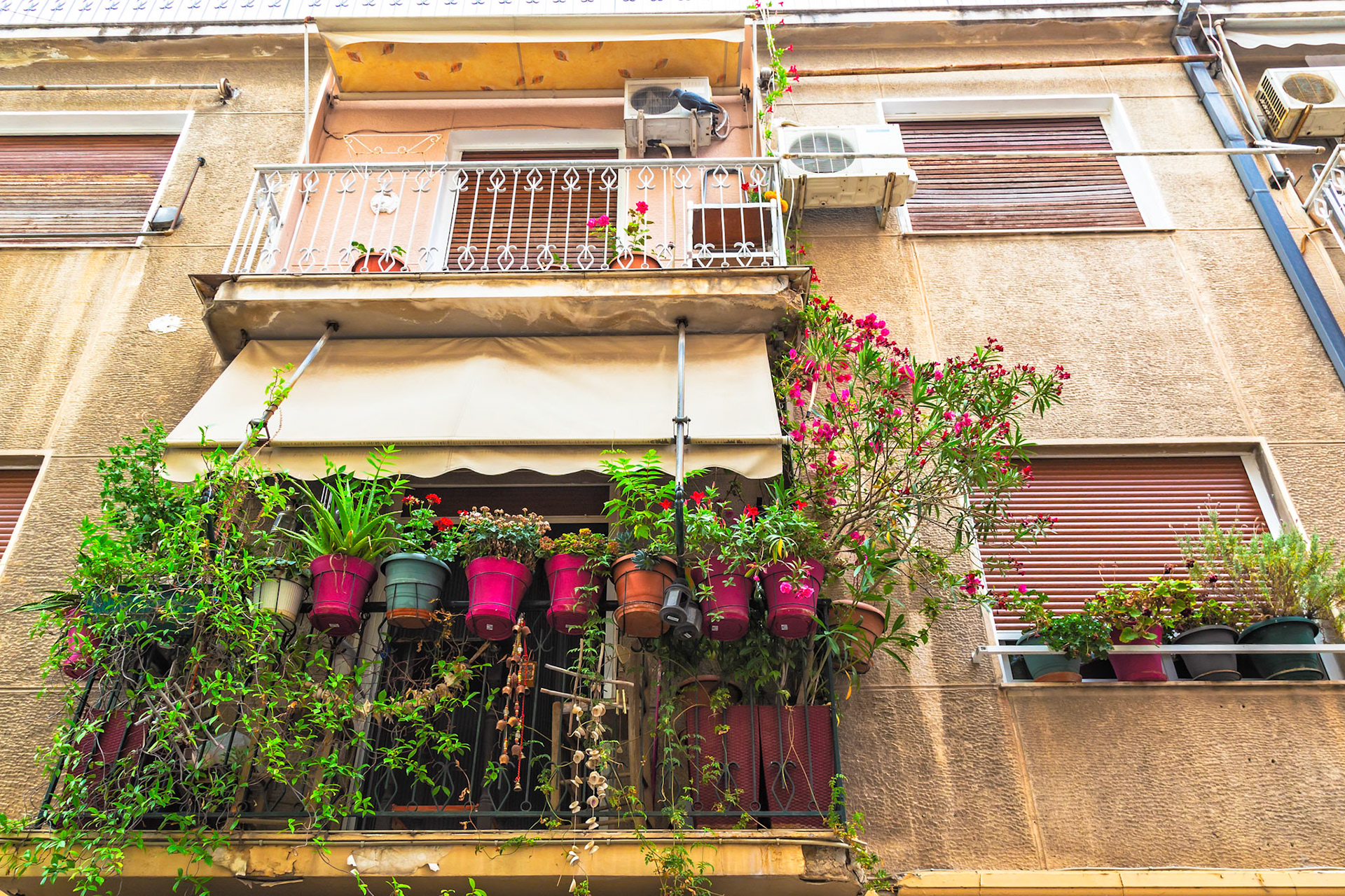 Athens, Greece - May 23rd 2018: A building's balconies are adorned with potted plants and flowers, adding natural beauty to the urban landscape.