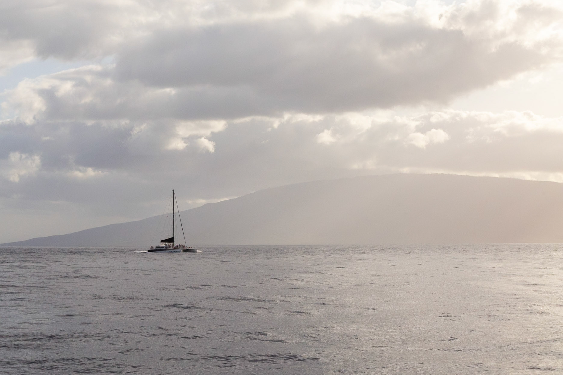 Maui, Hawaii, USA - April 7th 2022: A sailboat is sailing on the ocean with people on board, enjoying a tour or sunset cruise.