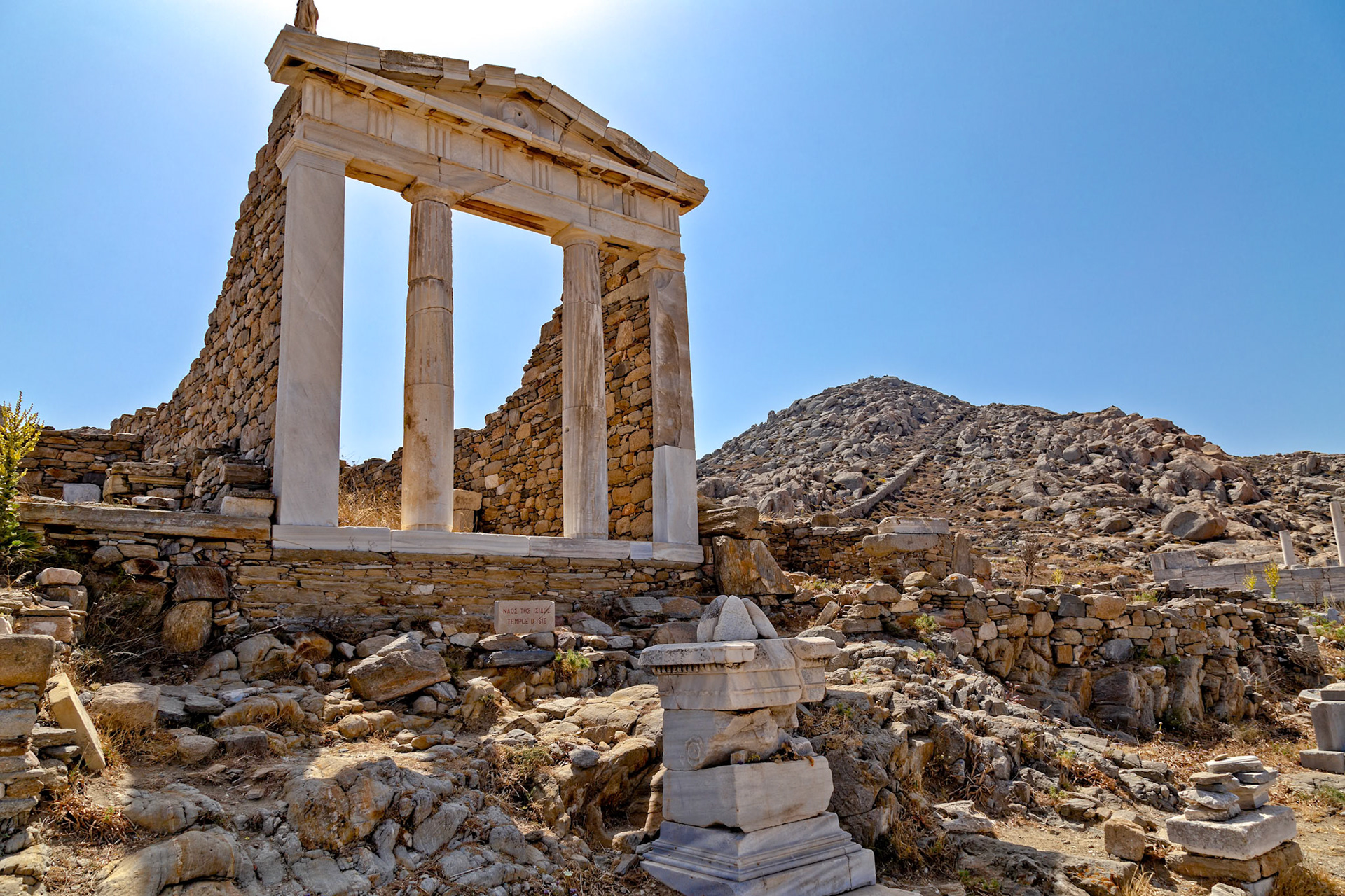 Delos, Greece - May 22nd 2018: Ruins of the Temple of Isis stand against a clear sky. The temple, dedicated to the Egyptian goddess, showcases ancient Greek architecture.