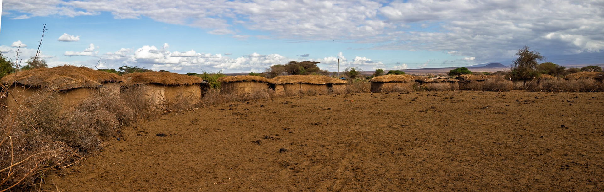 A Maasai village in Kenya shows traditional mud huts with thatched roofs, reflecting their culture and way of life.