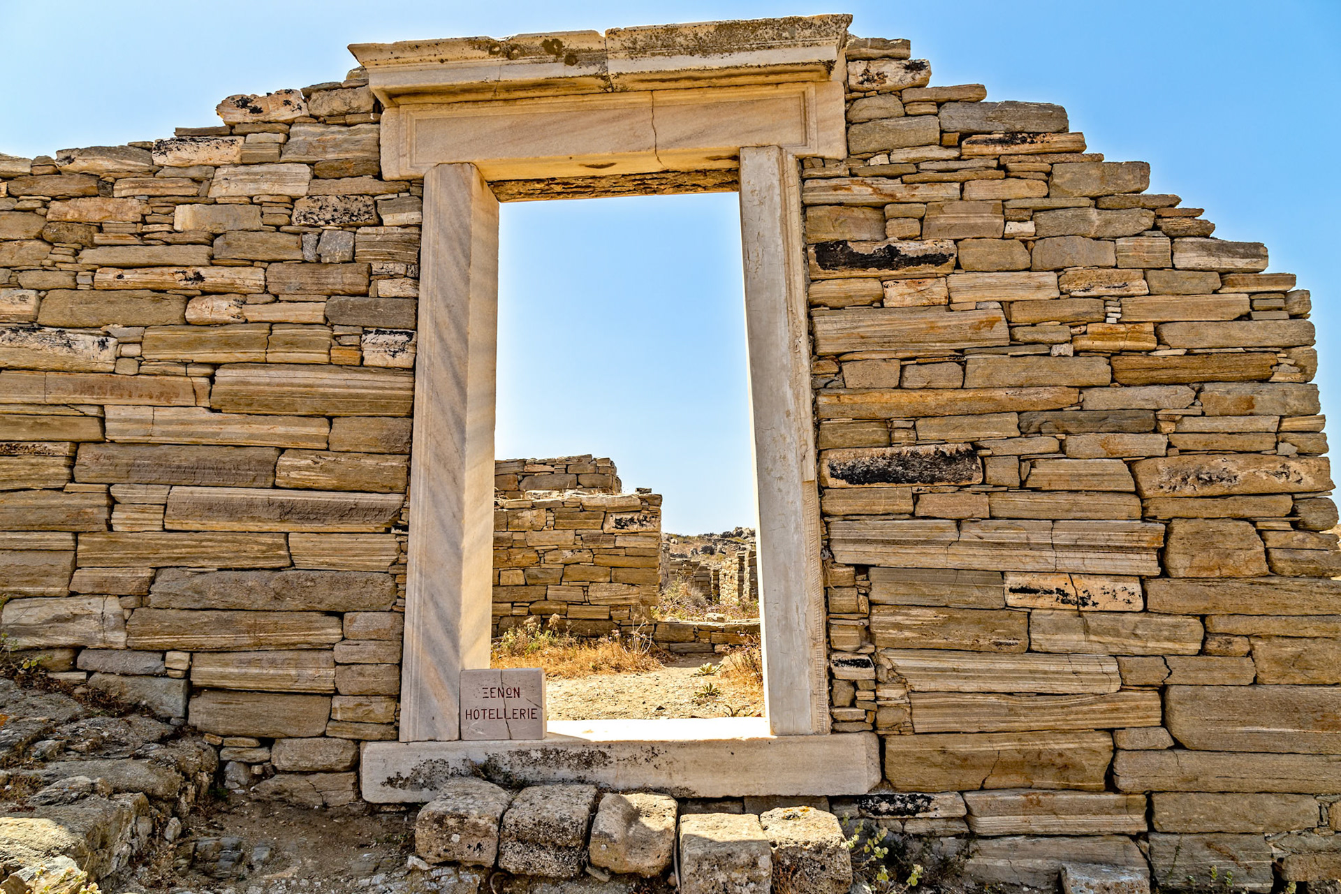 Delos, Greece - May 22nd 2018: Ancient stone ruins stand against a clear sky, showcasing the historical architecture and cultural heritage of Delos.