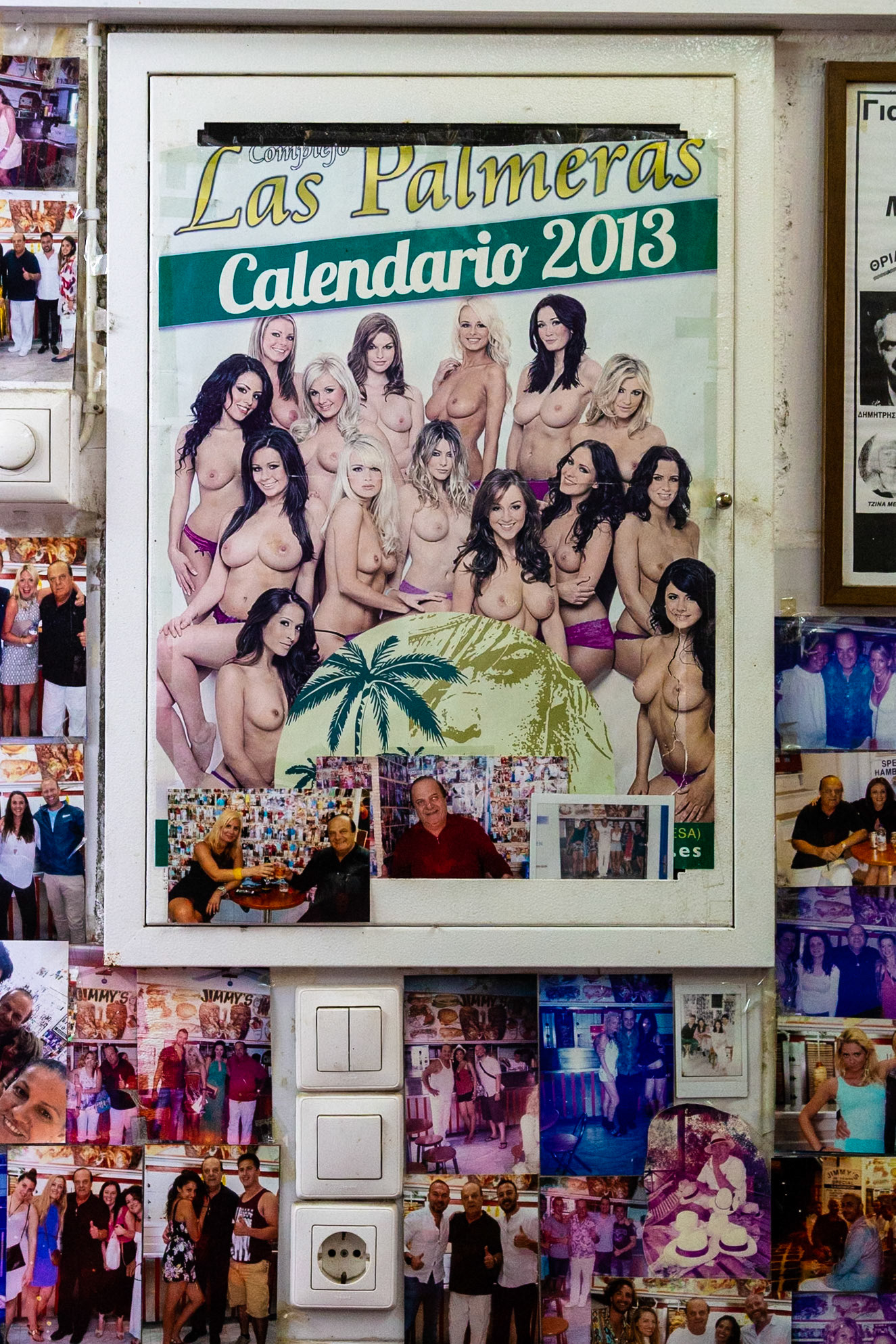 Mykonos, Greece - May 22nd 2018: A "Las Palmeras Calendario 2013" poster is surrounded by photos of people, possibly at Jimmy's restaurant.