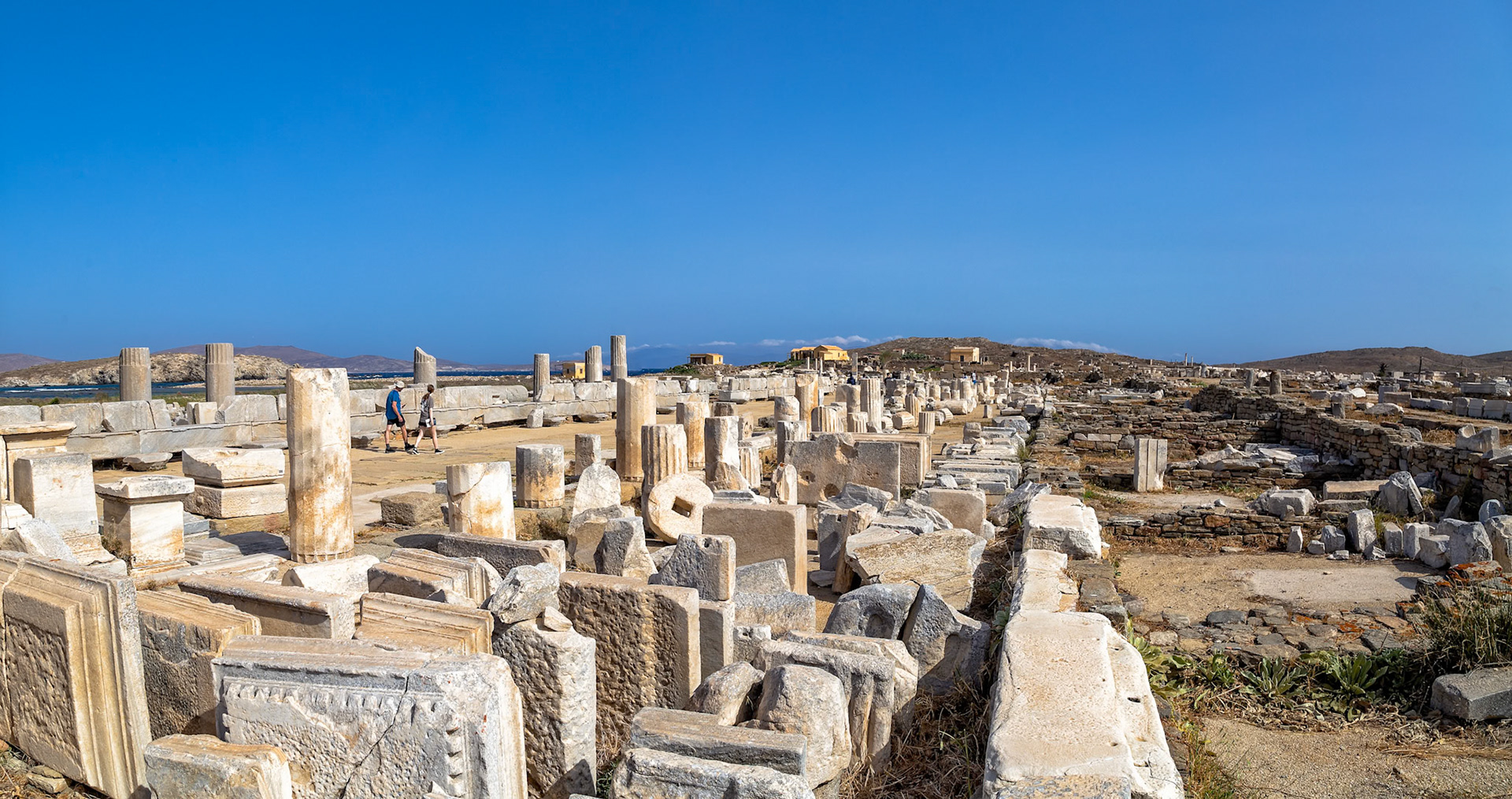 Delos, Greece - May 22nd 2018: Tourists explore the ancient ruins of Delos, a UNESCO World Heritage site, to learn about Greek history and culture.