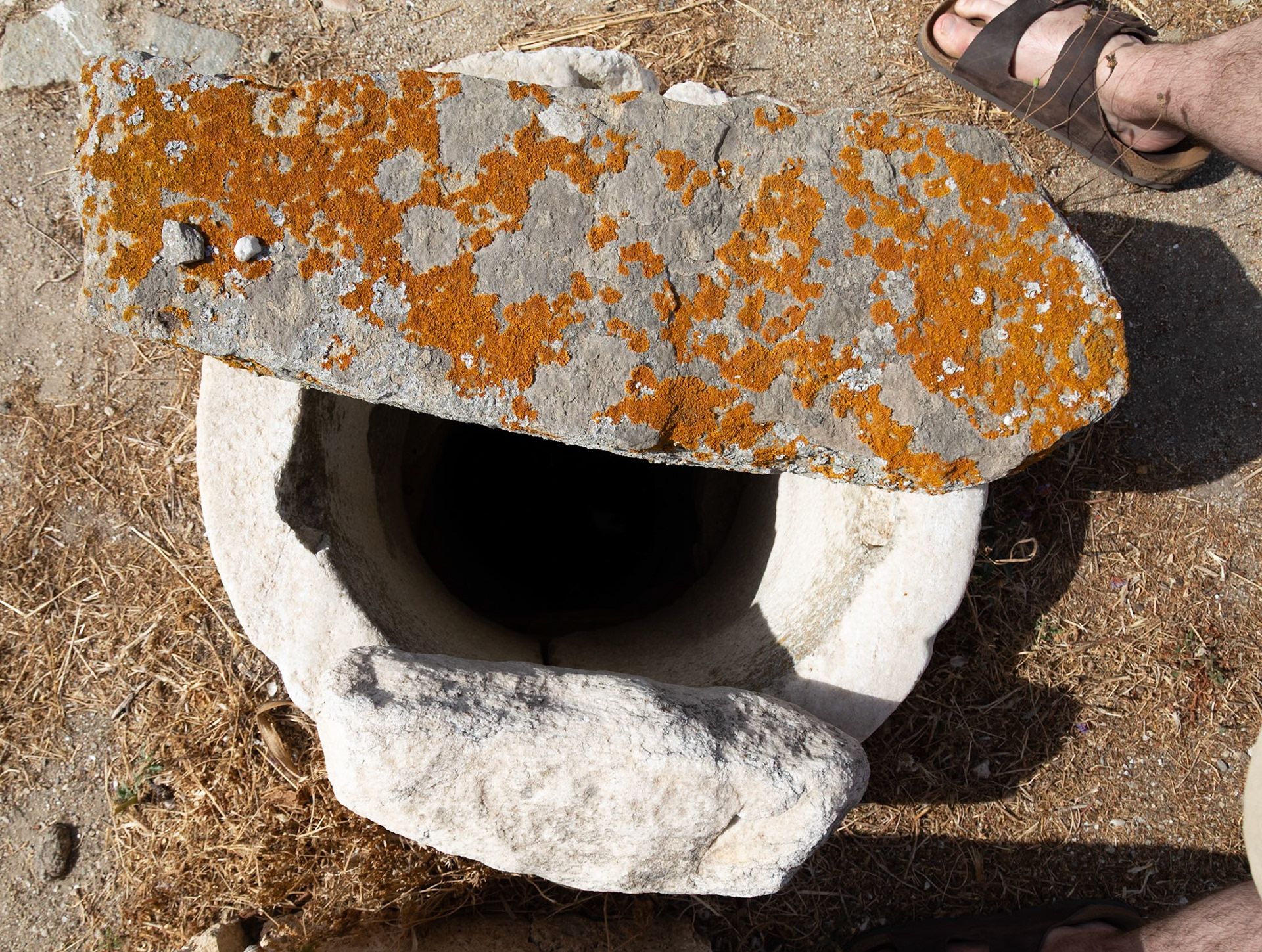 Delos, Greece - May 22nd 2018: An ancient stone well, possibly used for water storage, sits on the island of Delos, showcasing the island's rich history and archeological significance.