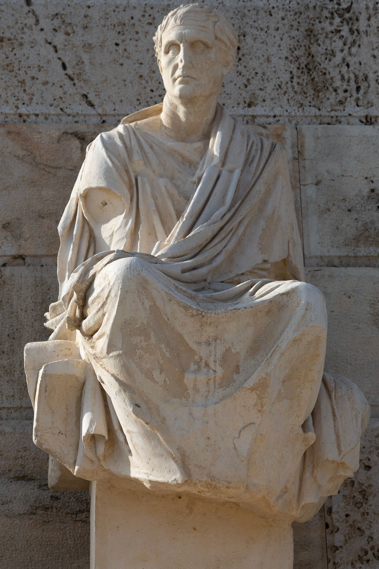Acropolis, Athens, Greece - May 23rd 2018: A statue of a seated man in a toga, likely a philosopher or statesman, stands as a testament to ancient Greek culture.