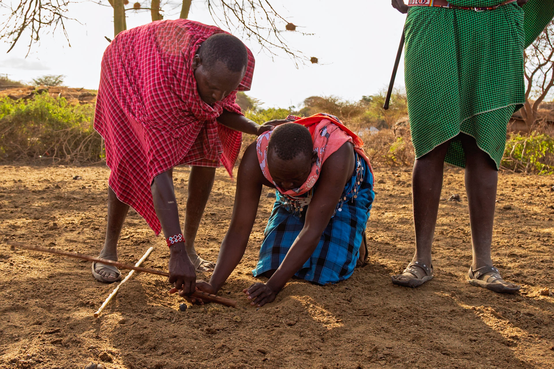 Maasai people in Kenya demonstrate starting a fire with sticks, a traditional skill passed down through generations.