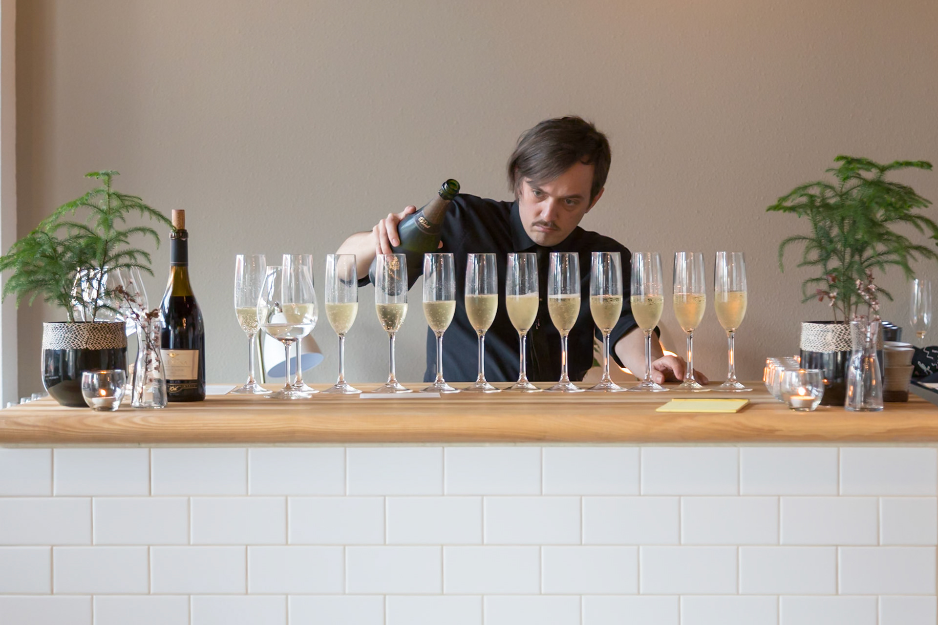 Fog Lark, Portland, Oregon - April 6th 2018: A bartender pours sparkling wine into a row of glasses, preparing for a tasting event.