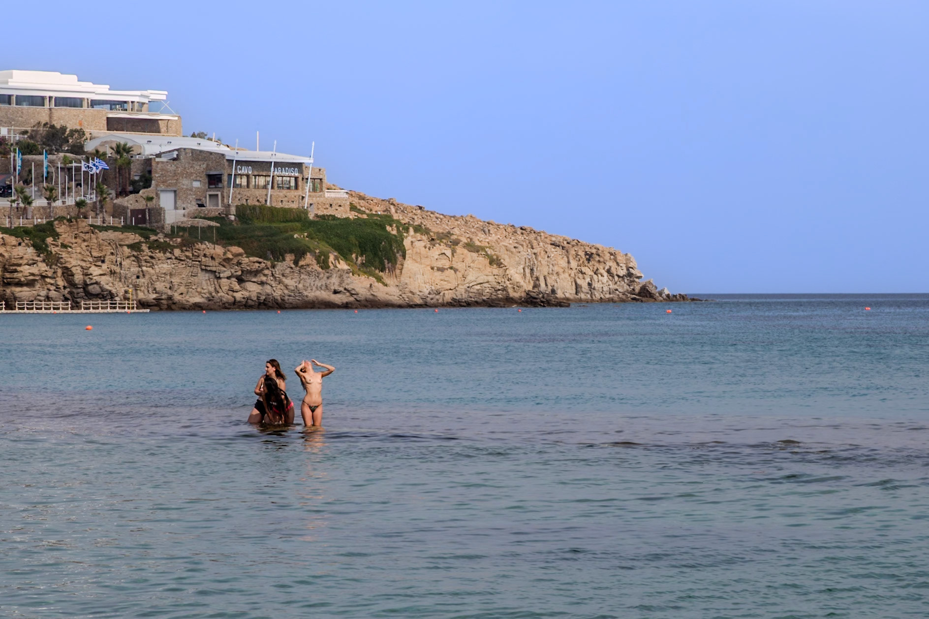 Paradise Beach, Mykonos, Greece - May 24th 2018: People are enjoying the cool water on a warm day at Paradise Beach in Mykonos, Greece.