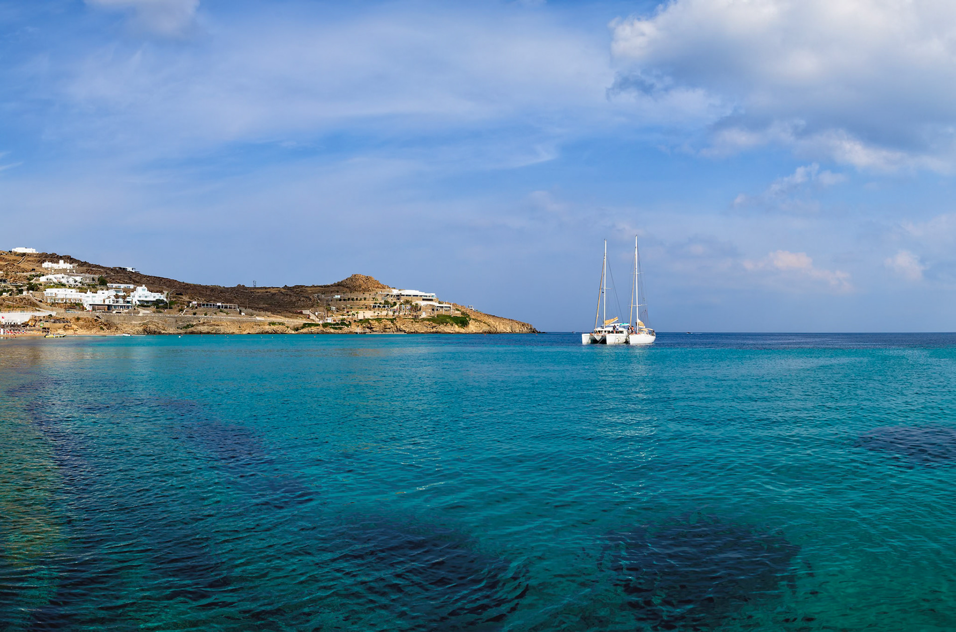 Paradise Beach, Mykonos, Greece - May 24th 2018: A catamaran sits in the turquoise water, offering a scenic view for tourists on the Greek island.