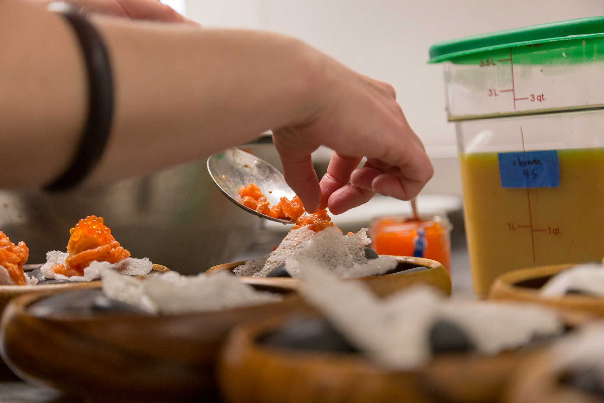 Fog Lark, Portland, Oregon - April 6th 2018: A chef carefully plates salmon roe atop a delicate rice cracker, preparing appetizers for an event.